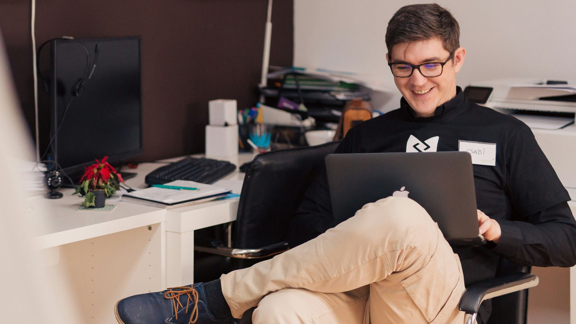 man smiling while sitting and using MacBook