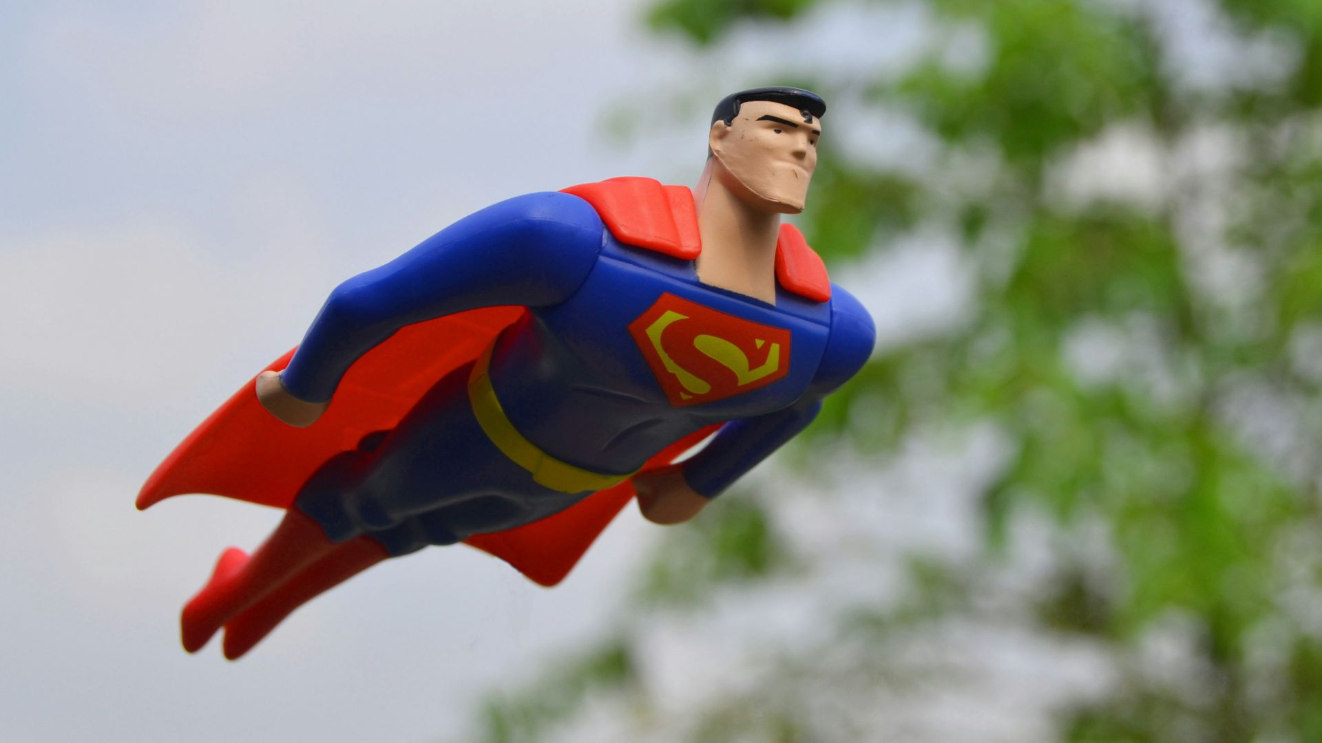 Superman flying near green grass