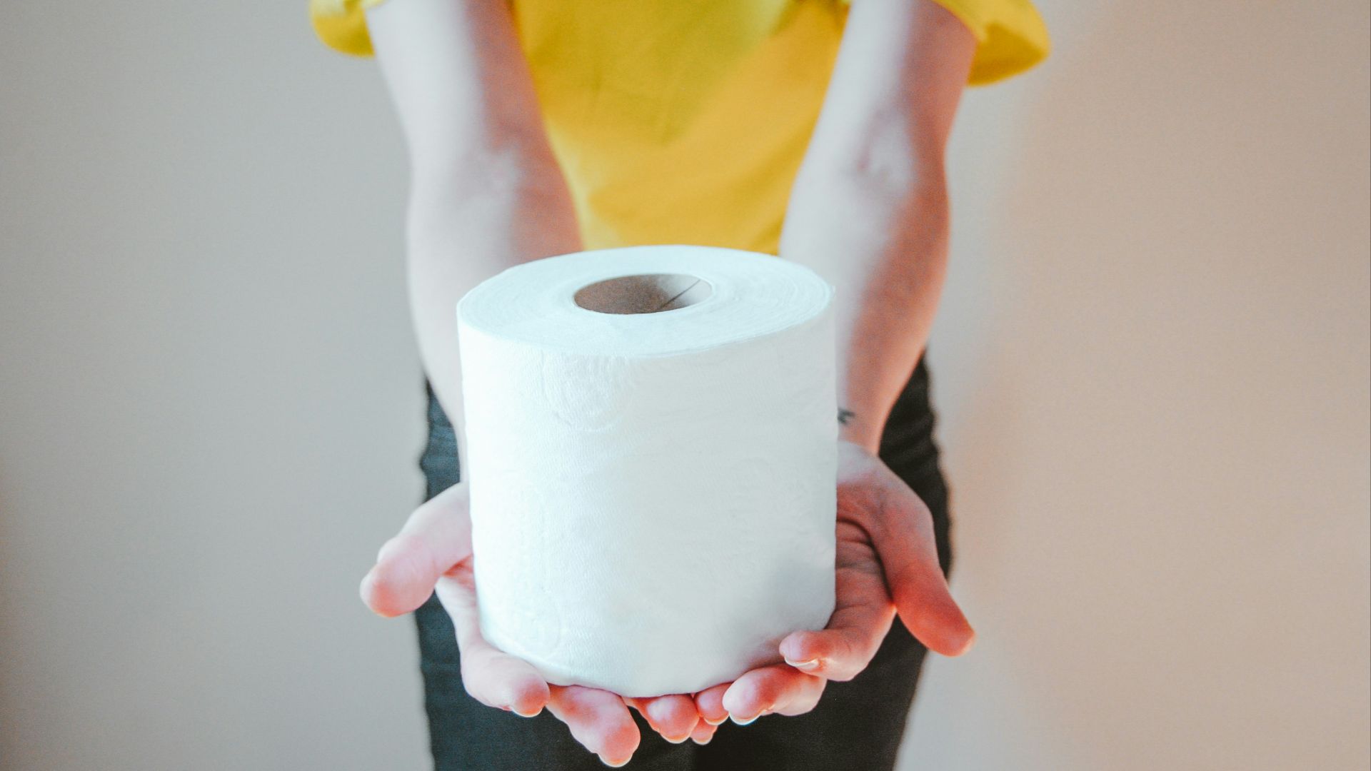 woman in yellow t-shirt holding white tissue paper