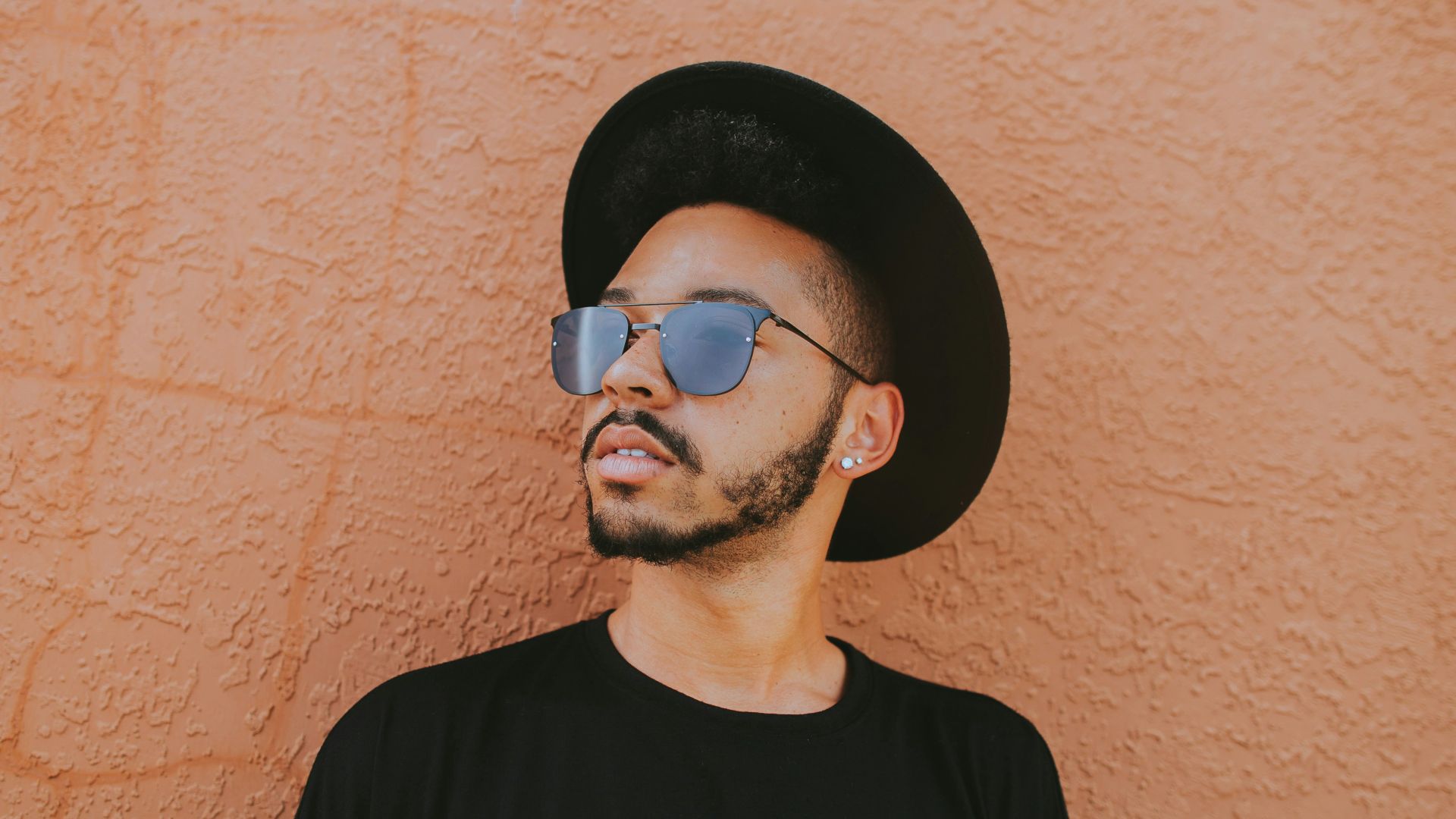 man leaning on brown wall