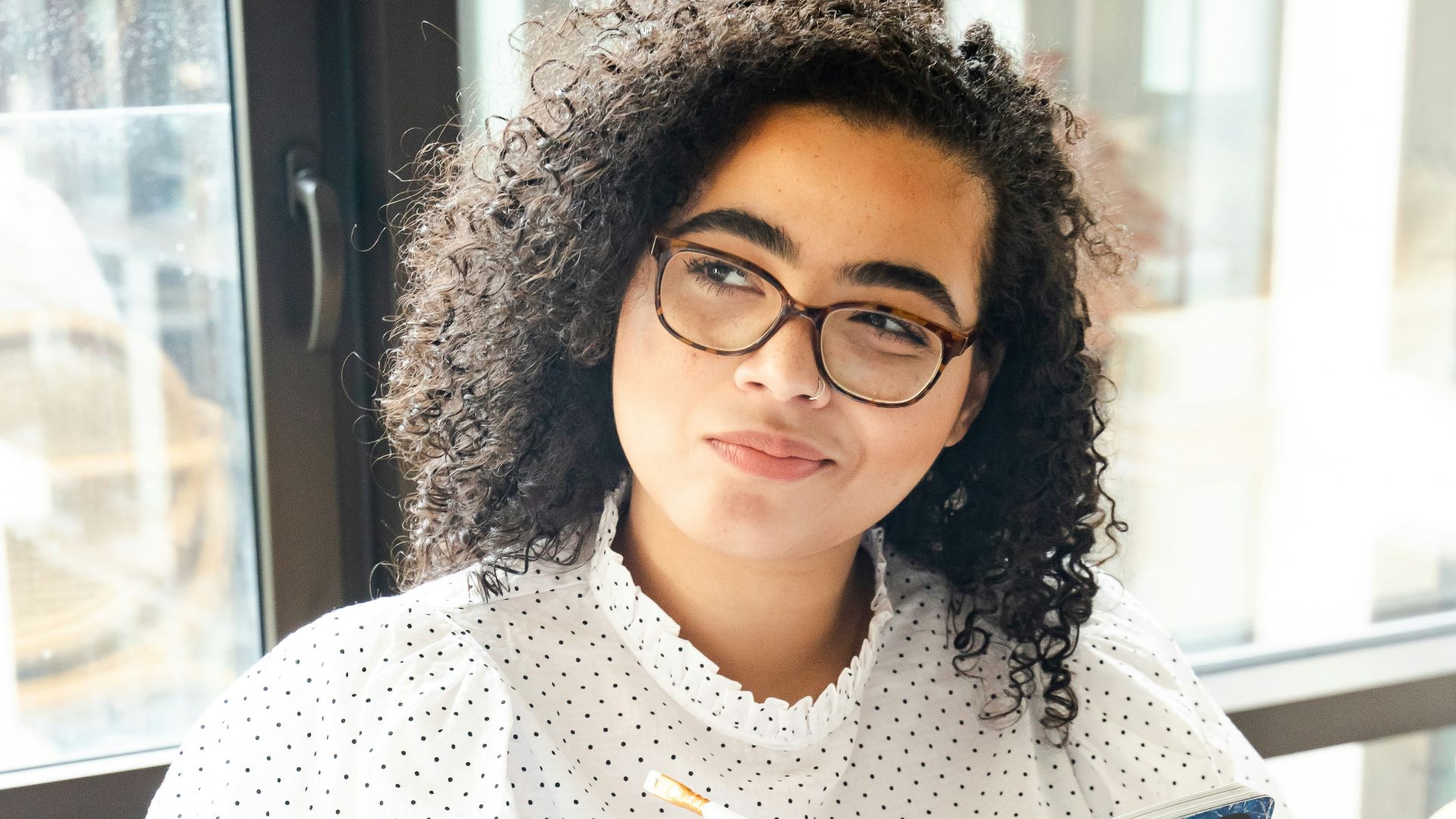 woman in white and black polka dot shirt holding blue and white book