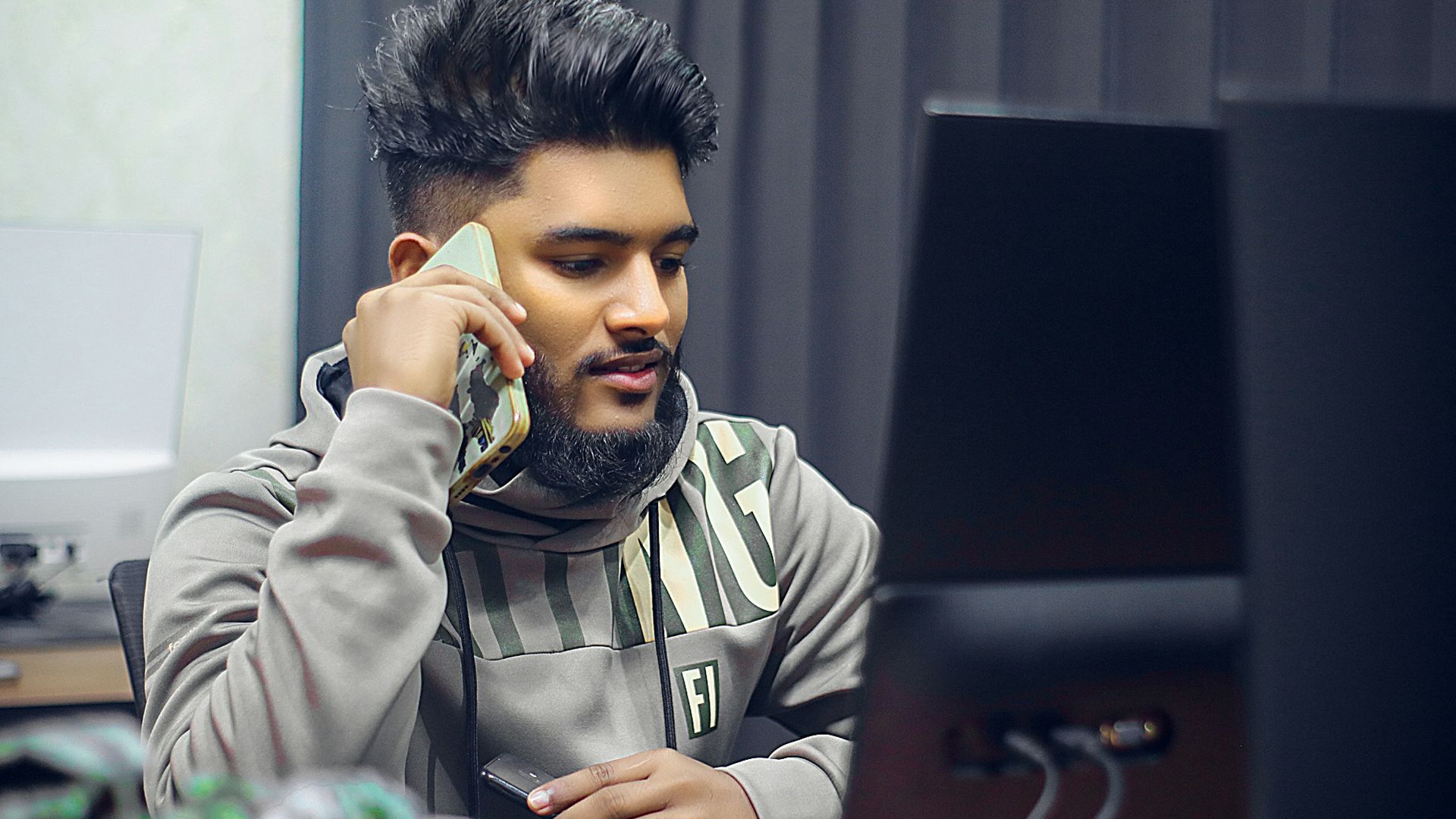 Man is on the phone in front of computer.