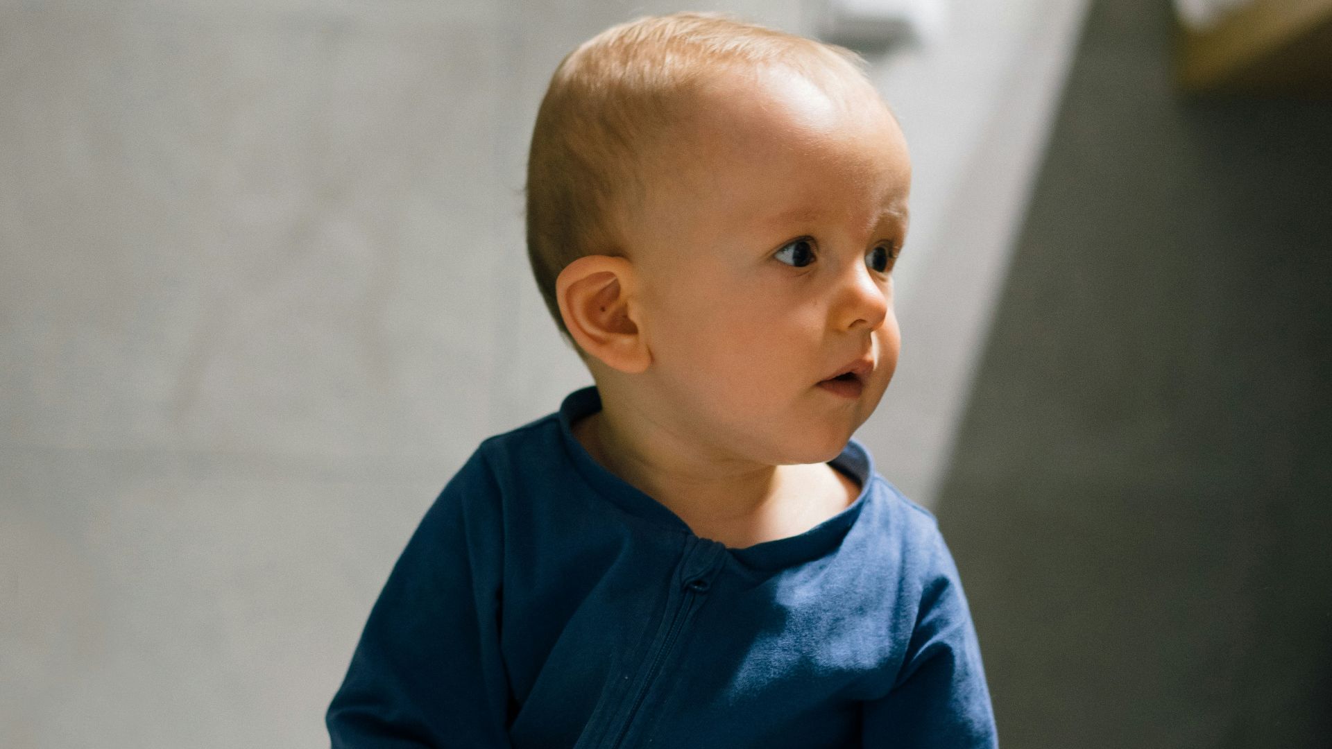 baby in blue long sleeve shirt and blue denim jeans sitting on floor