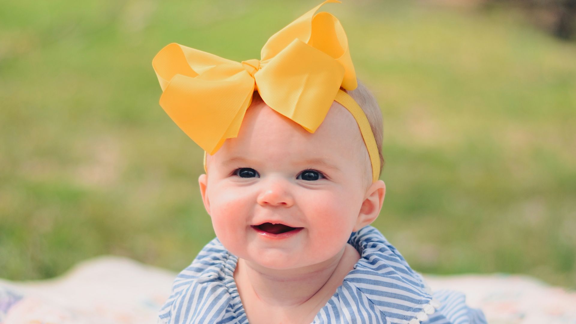 smiling baby lying forward on pink textile