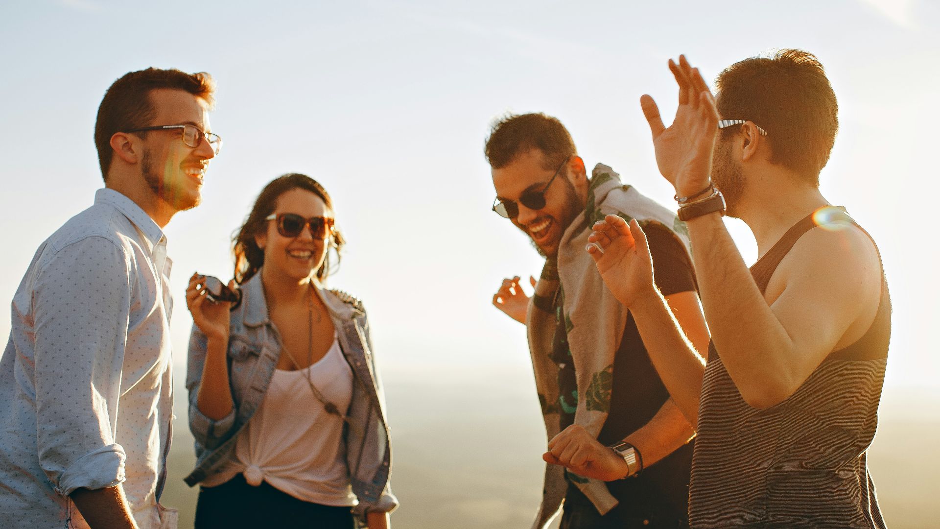 three men and one woman laughing during daytime
