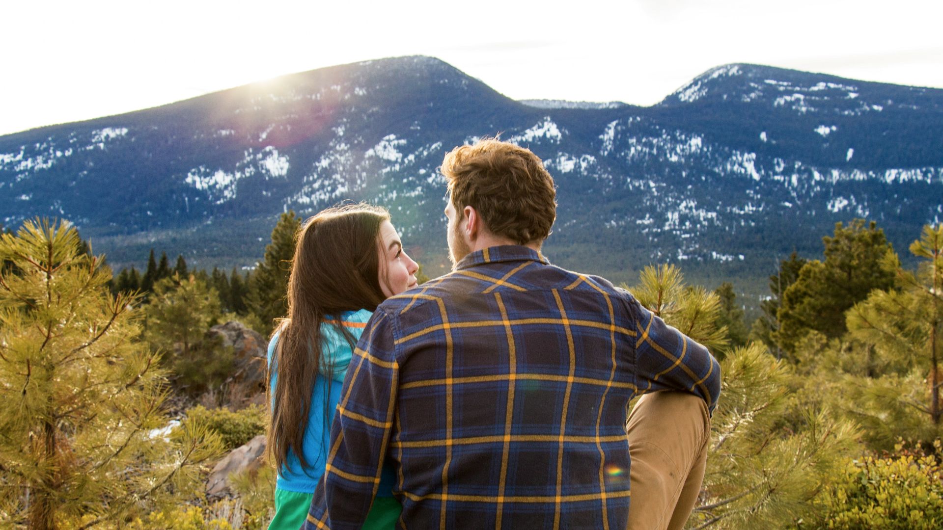 man and woman sitting on rack facing at mountain