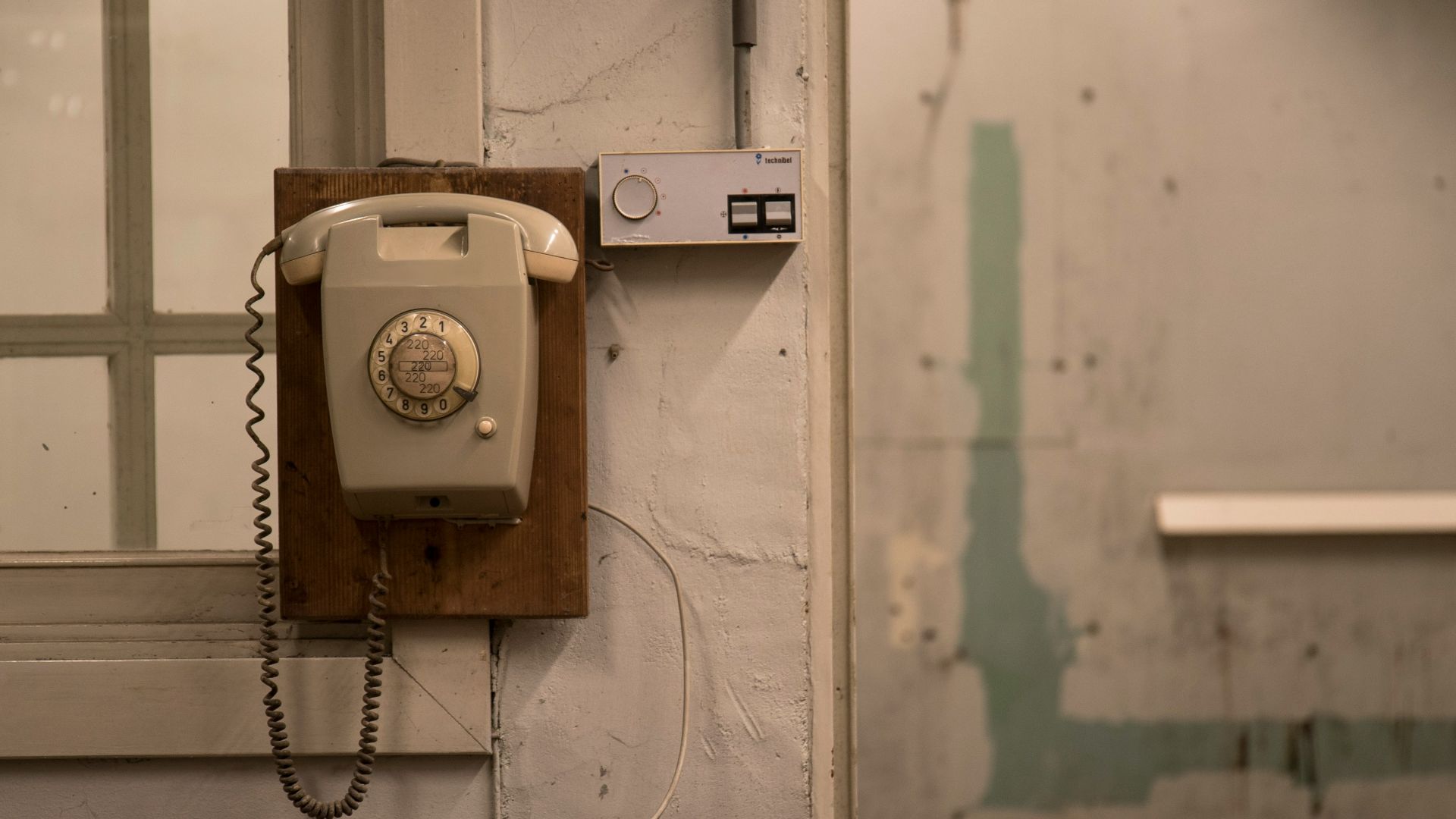 an old phone is hanging on a wall