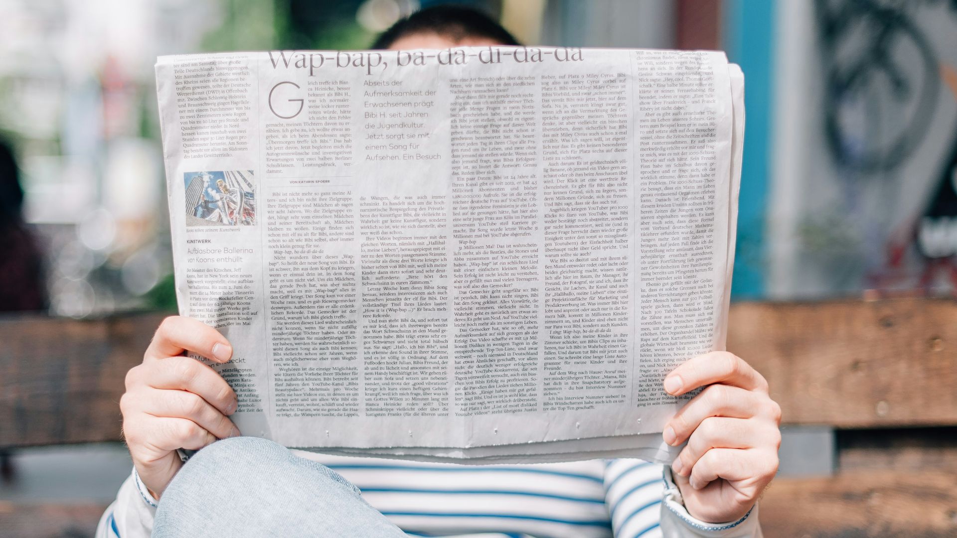 man sitting on bench reading newspaper