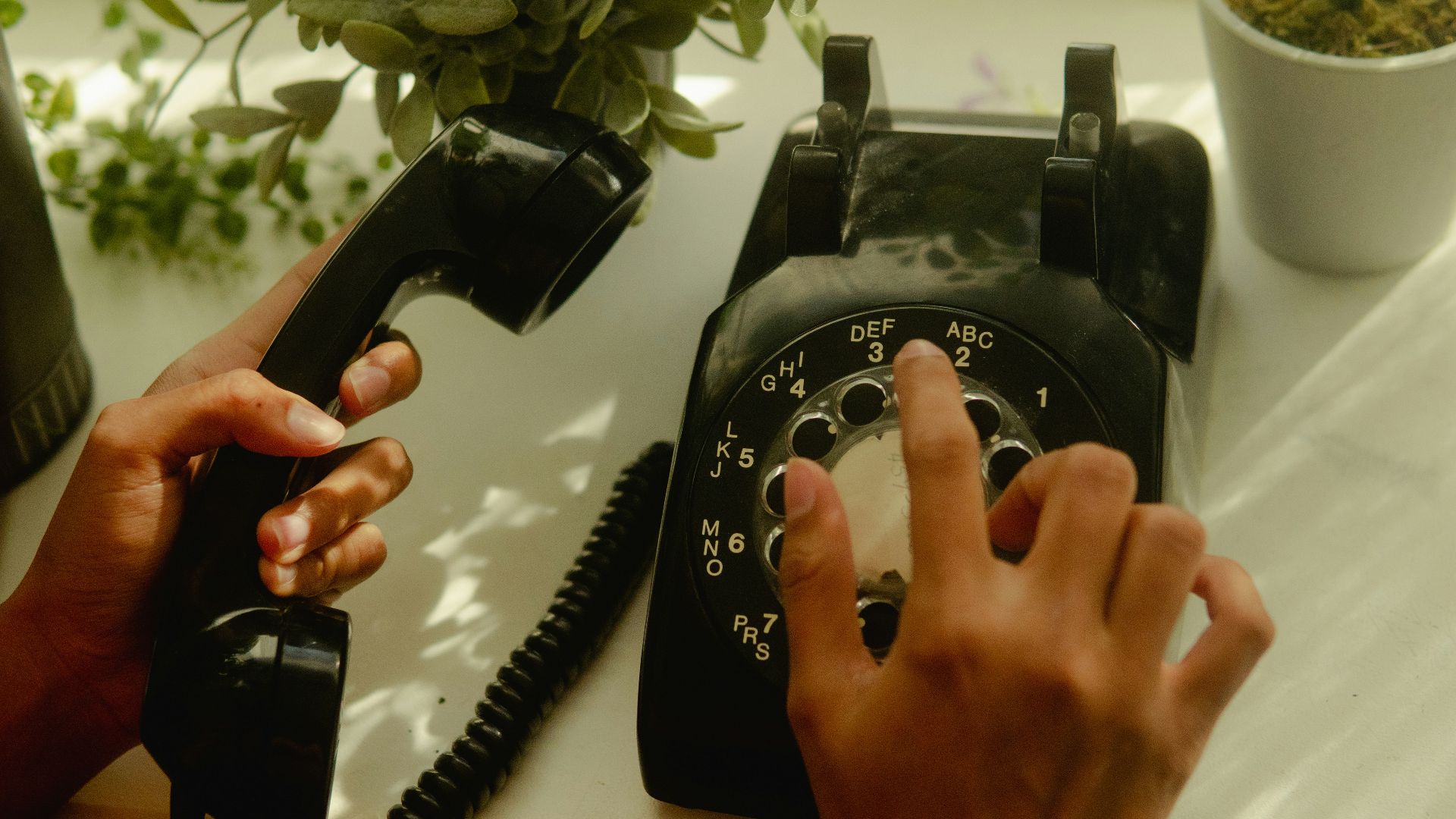 person holding black rotary telephone