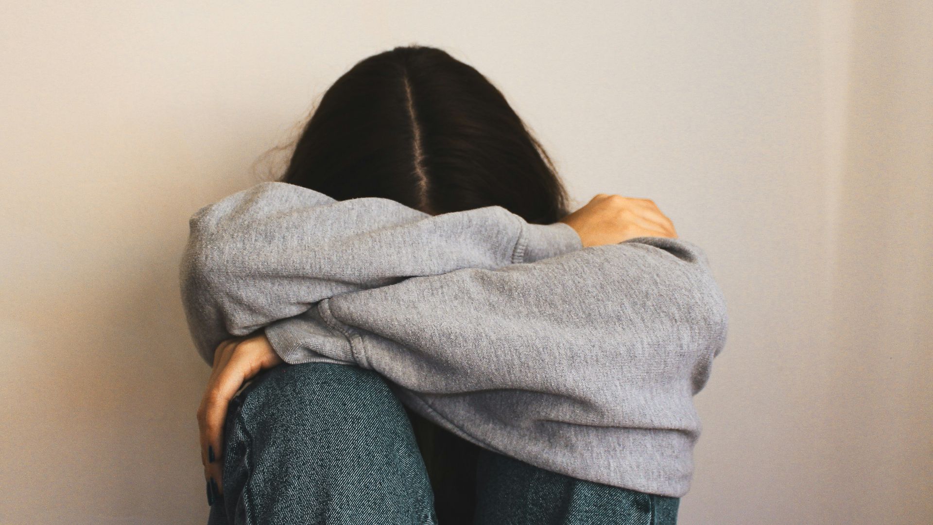 a woman sitting on the floor with her arms wrapped around her head