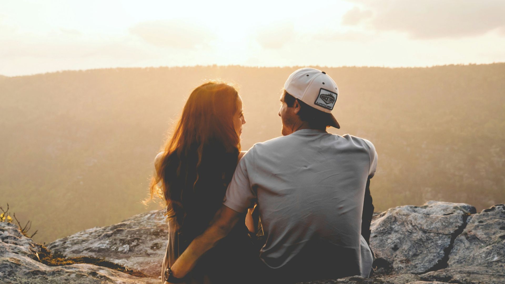 man and woman sitting on rock during daytime