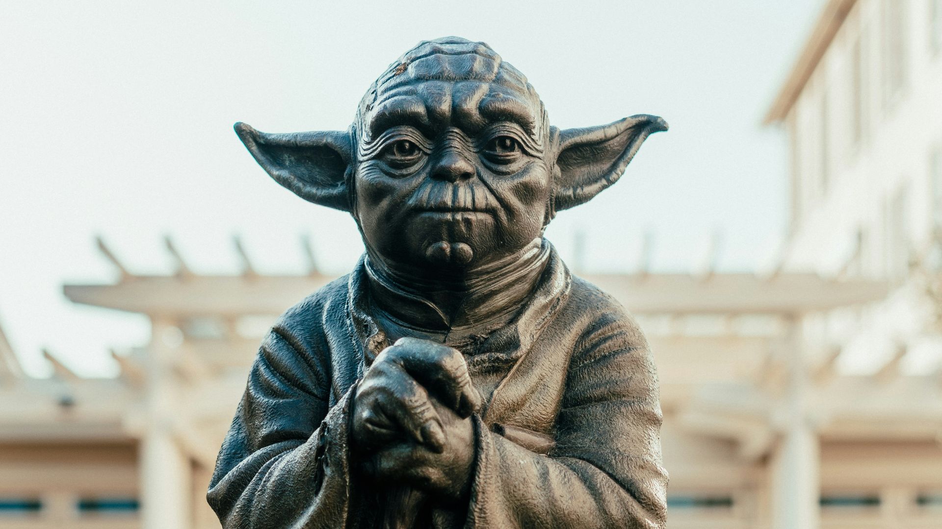 a statue of yoda holding a staff in front of a building