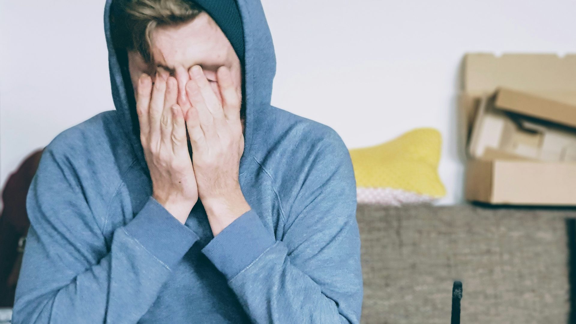 man covering face with both hands while sitting on bench