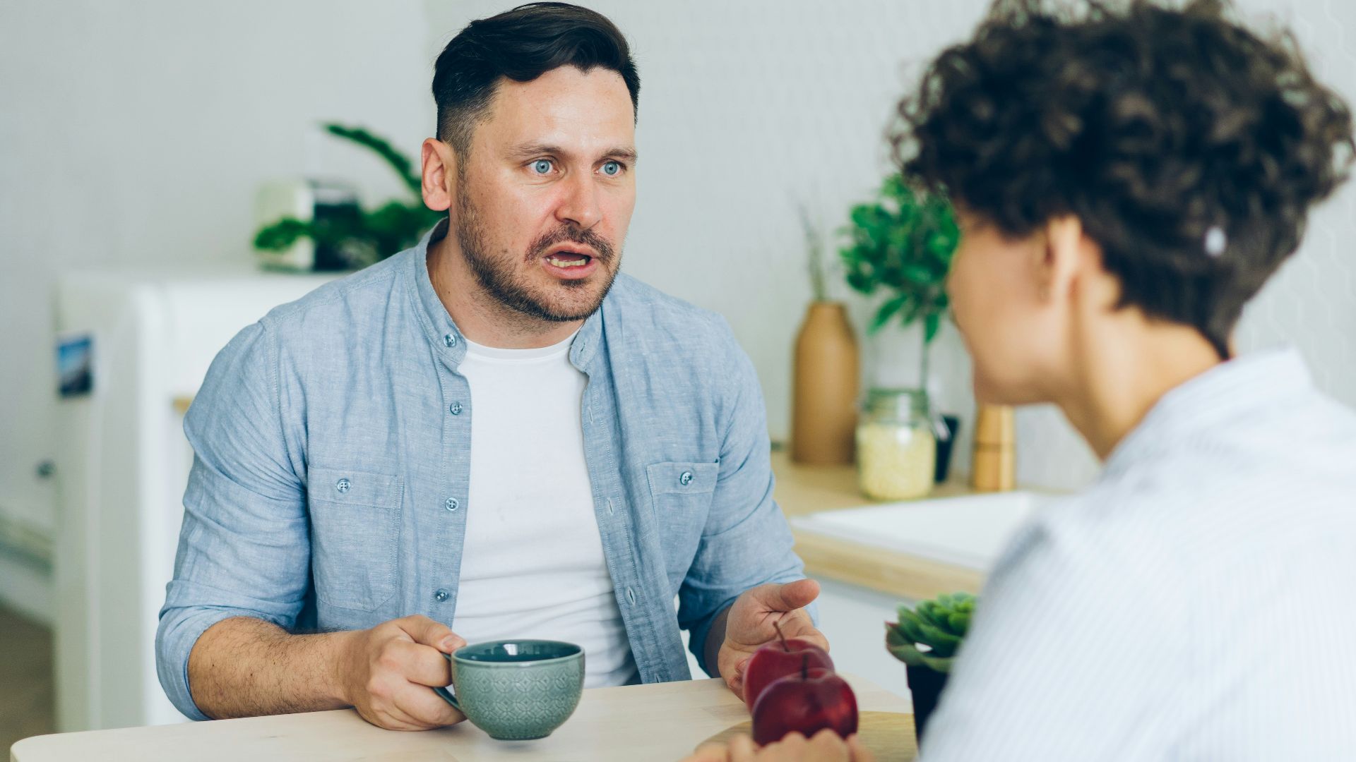 a man sitting at a table talking to a woman