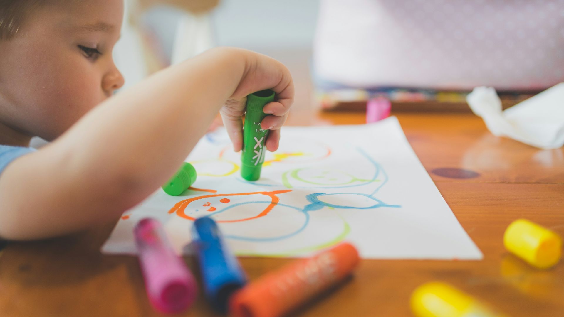 a little boy that is sitting at a table with some crayons