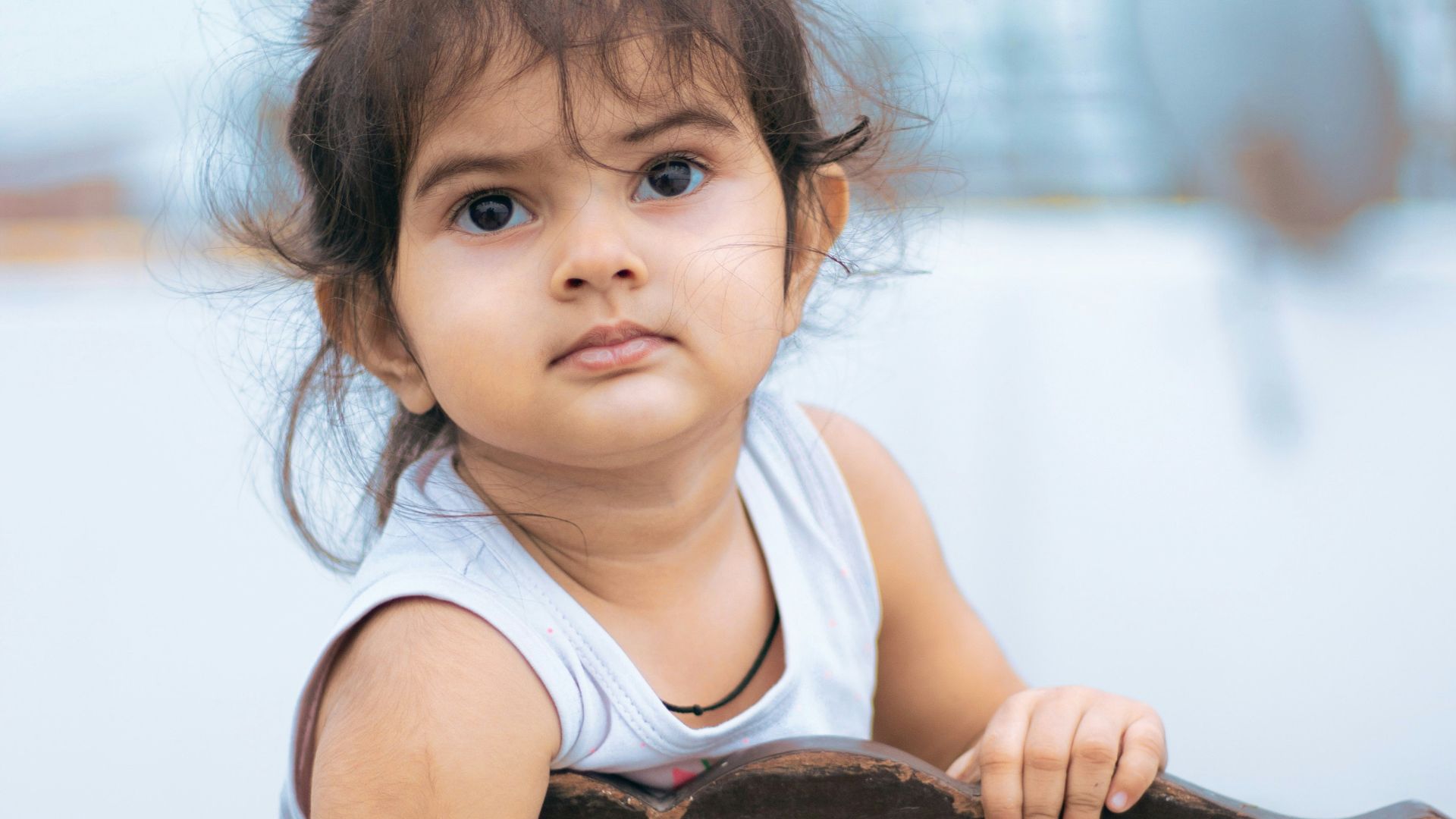 girl in white tank top sitting on brown wooden chair