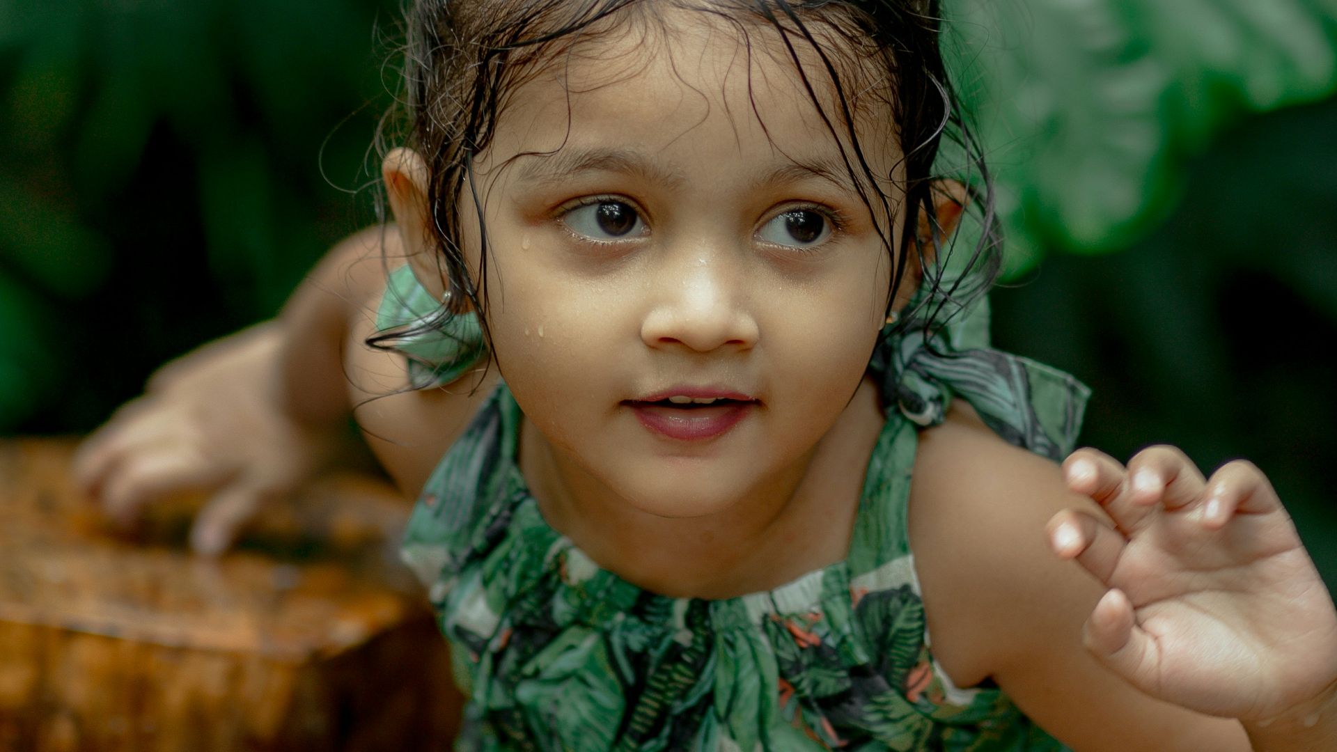 a little girl standing next to a tree stump