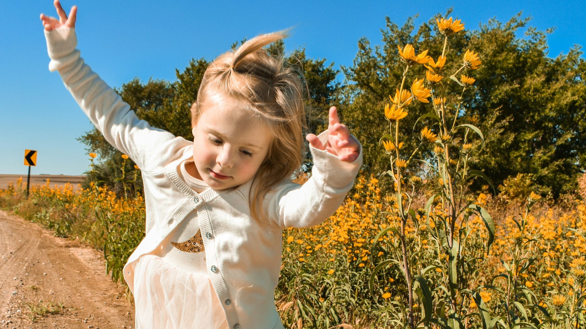 girl in white dress shirt and blue denim jeans standing on brown soil during daytime