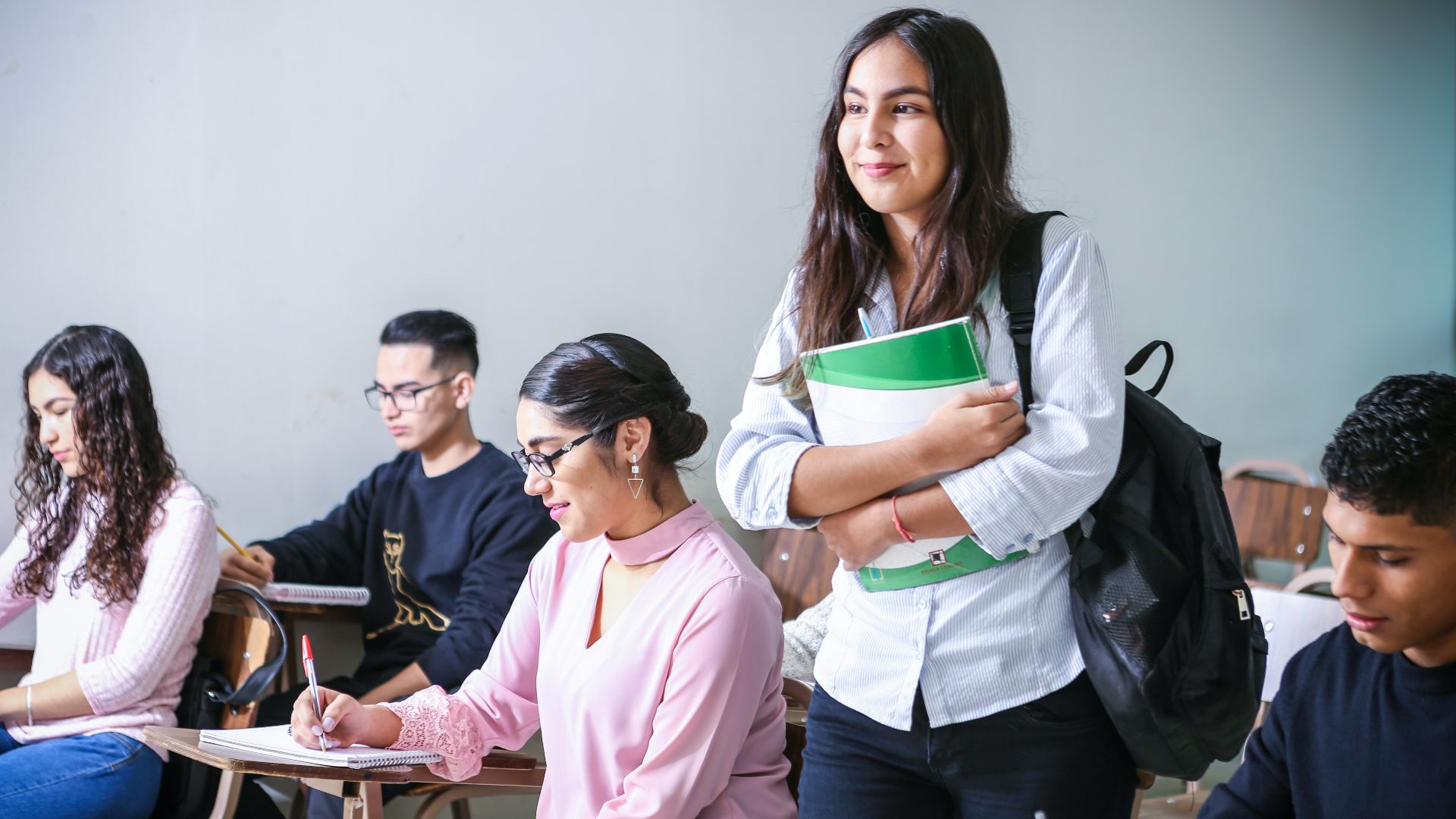 woman carrying white and green textbook