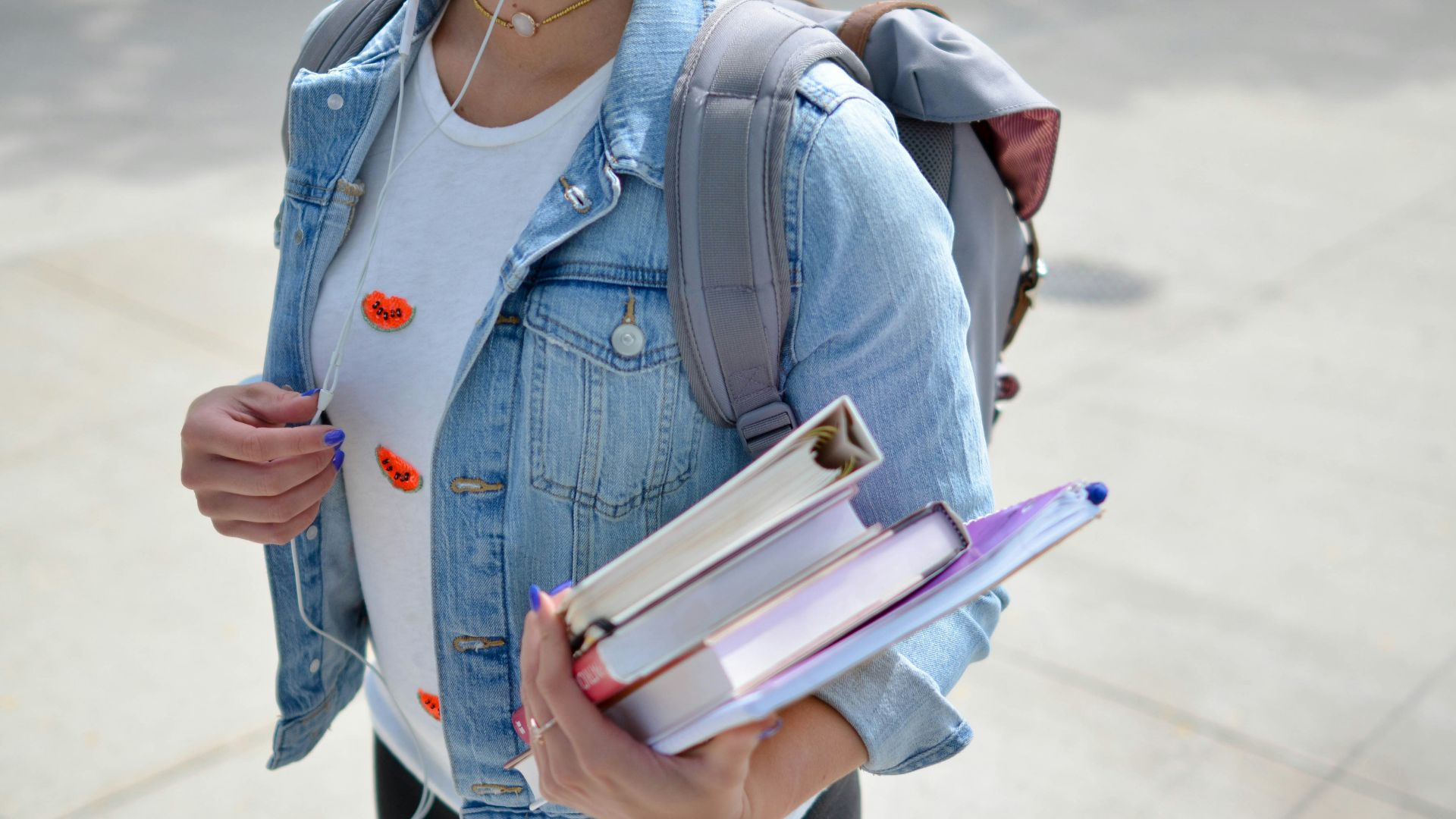 woman wearing blue denim jacket holding book