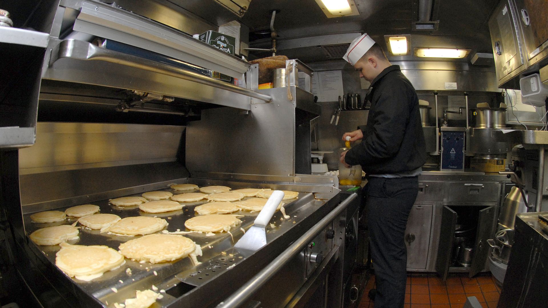 File:US Navy 081210-N-7668G-018 Culinary Specialist Seaman Apprentice Henry Kennedy, from Opelousas, La., prepares eggs as pancakes cook on the grill aboard the Los Angeles-class attack submarine USS Albany (SSN 753).jpg