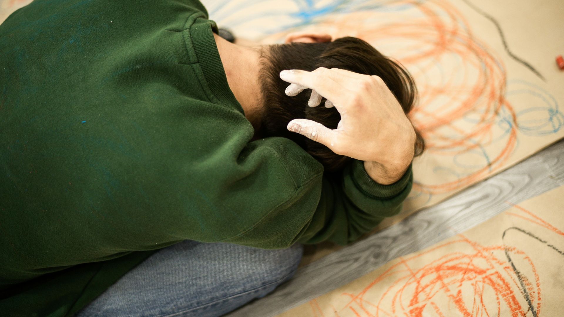 man in green sweater lying on bed