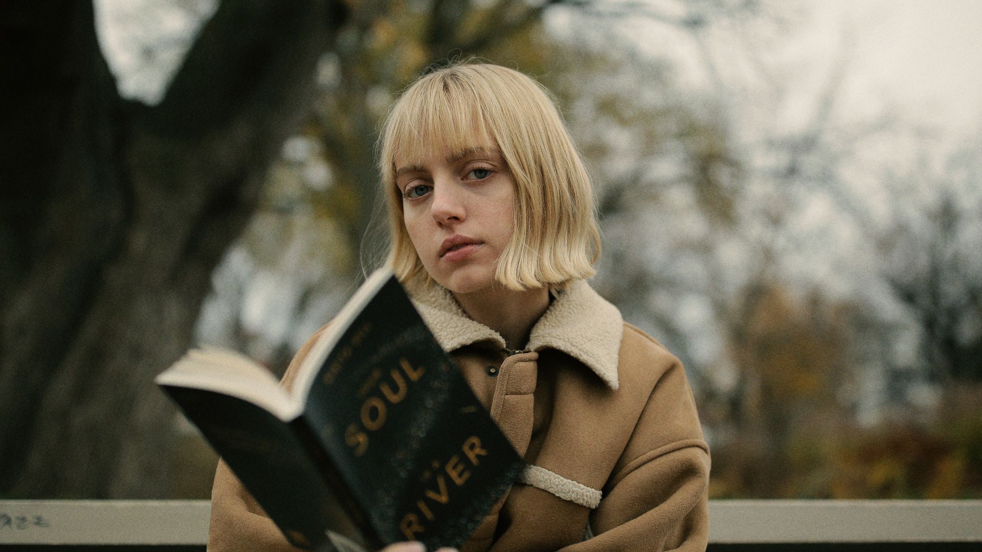 woman holding book while sitting on gray bench