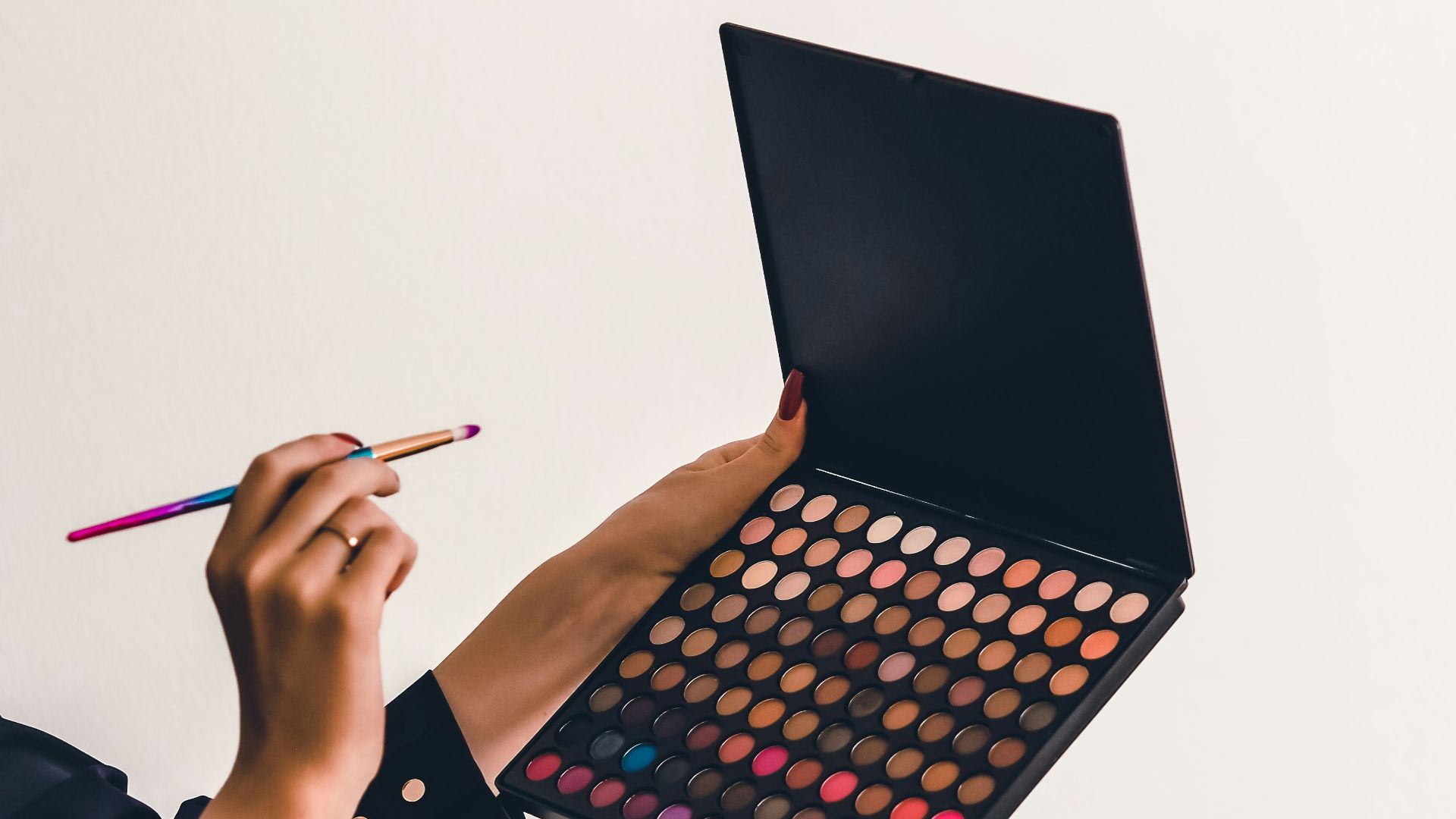 a person holding a makeup palette and a pencil