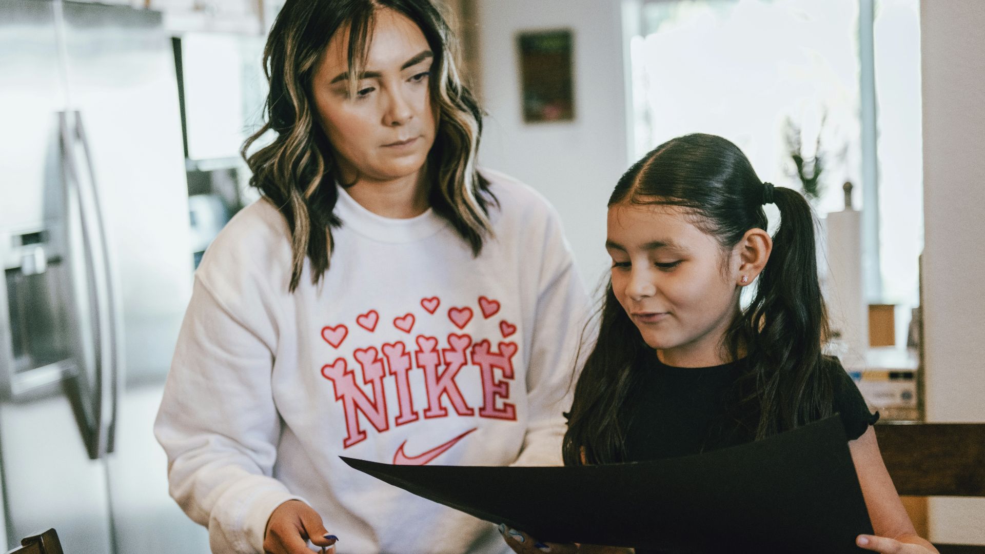a woman standing next to a little girl in a kitchen