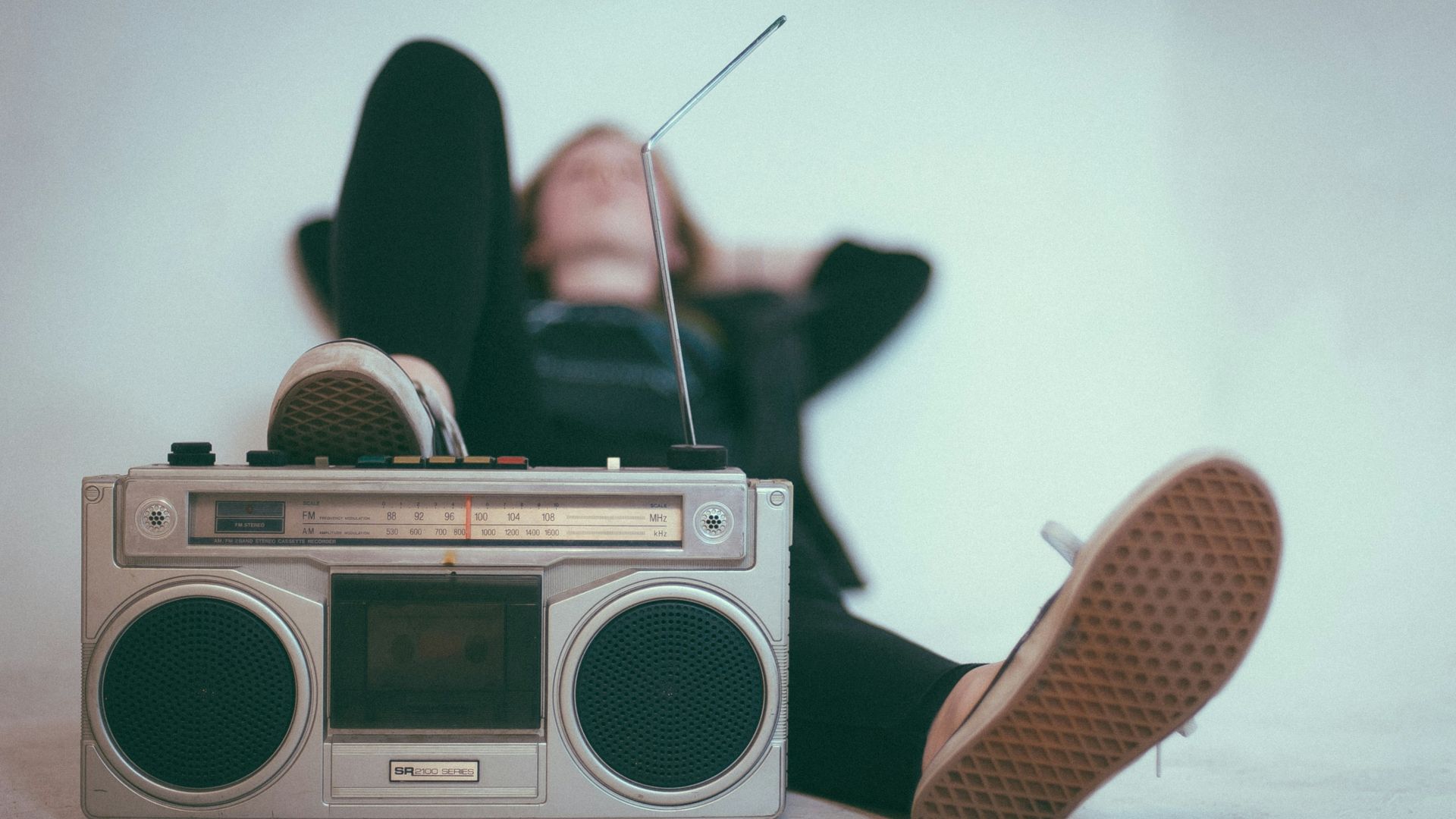 woman laying on bed near gray radio