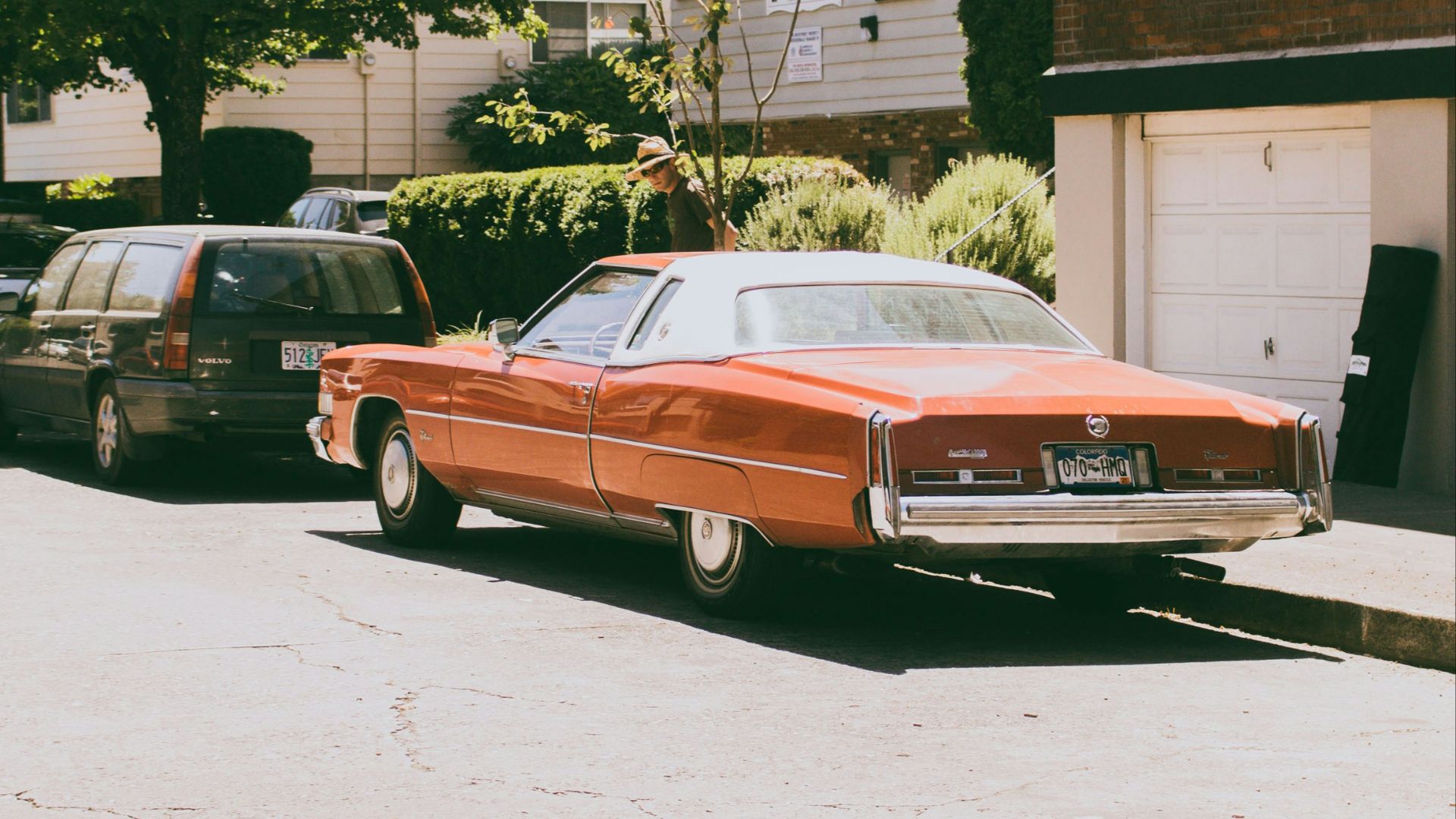 beige coupe park near brown high-rise building