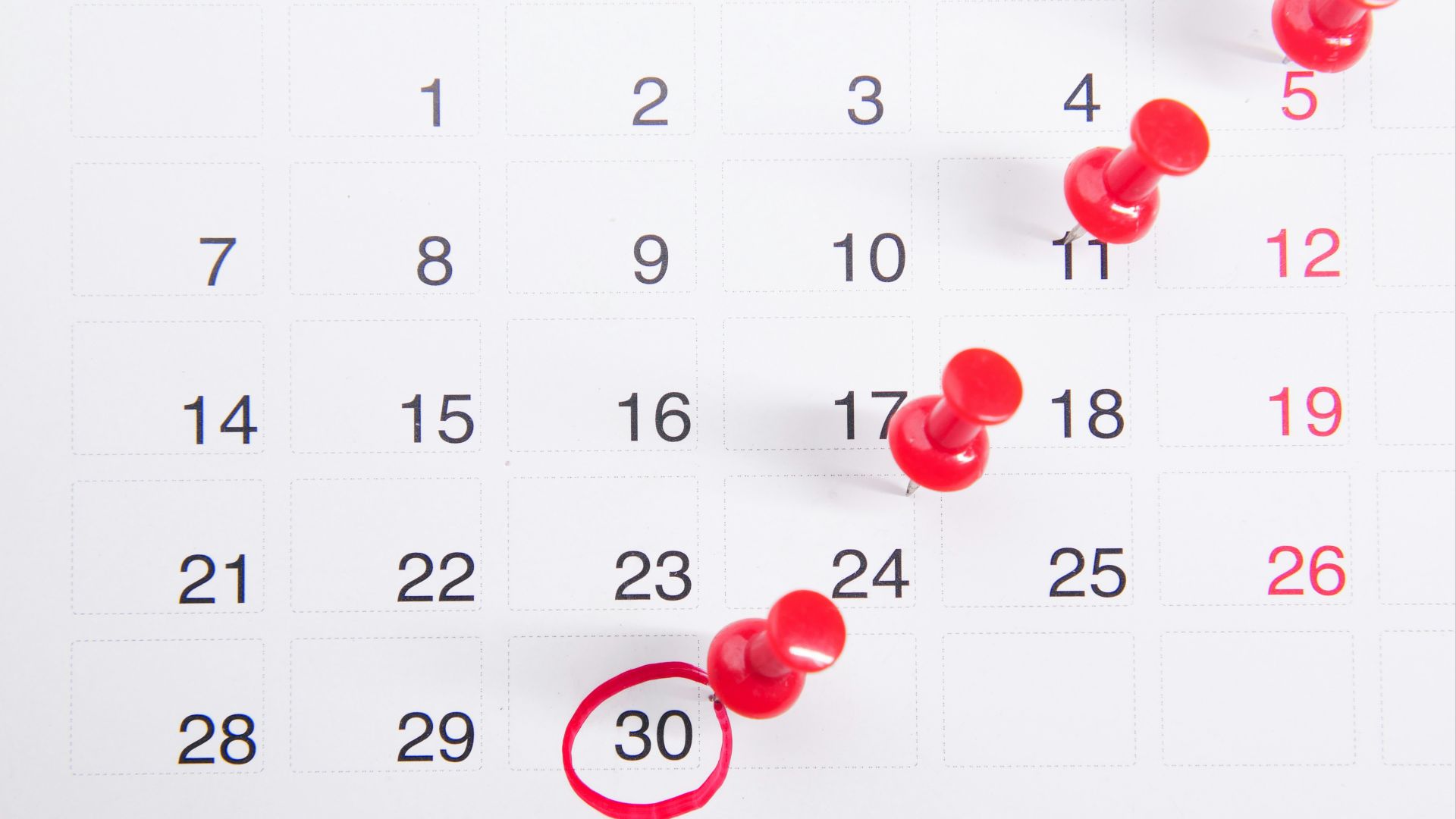 a calendar with red push buttons pinned to it