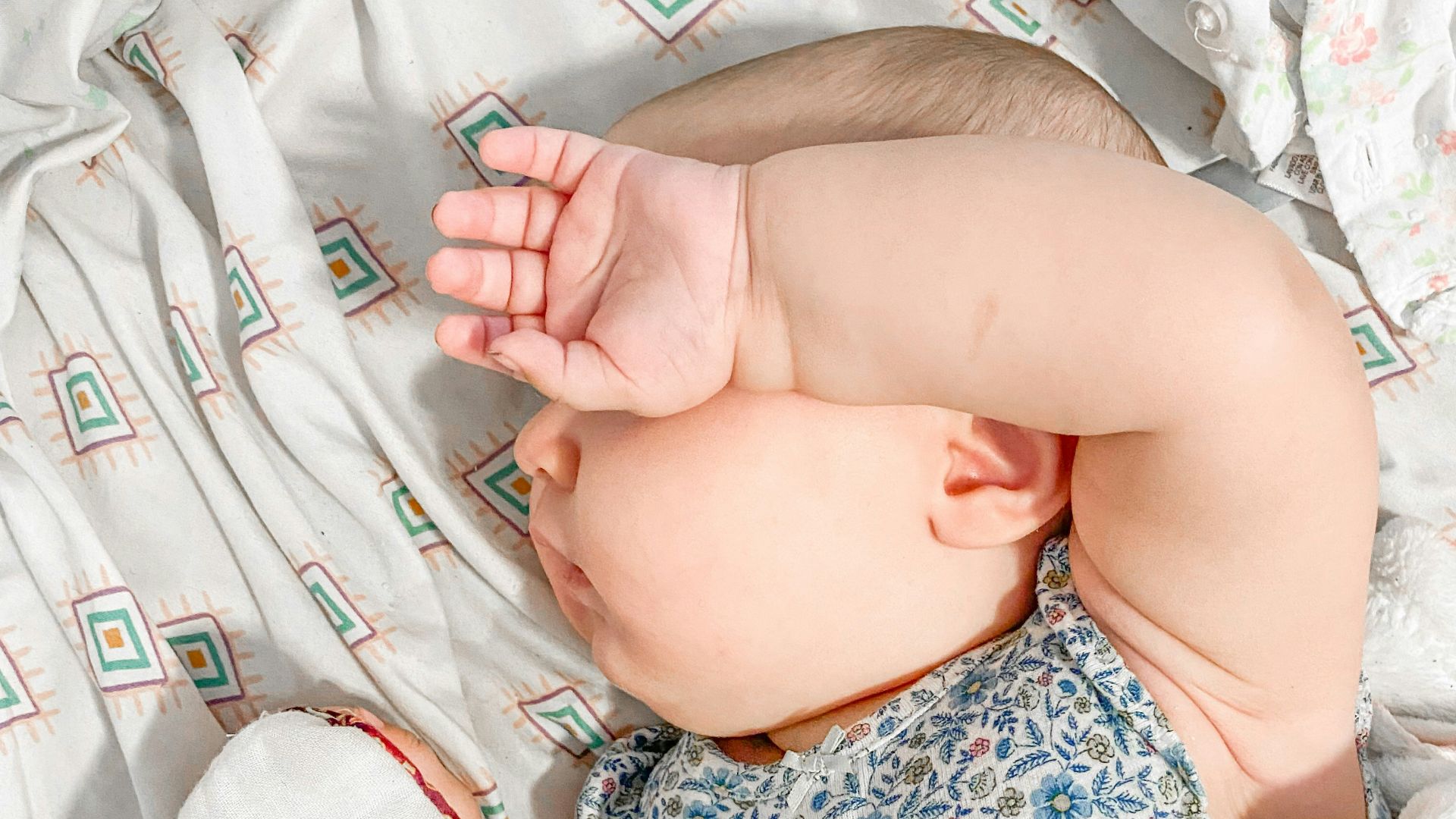 a baby laying on a bed with a white blanket
