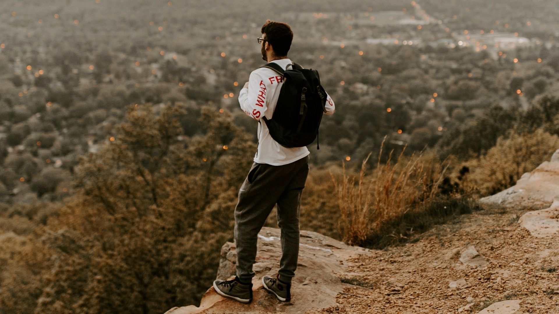 man in white shirt and black pants standing on brown rocky mountain during daytime