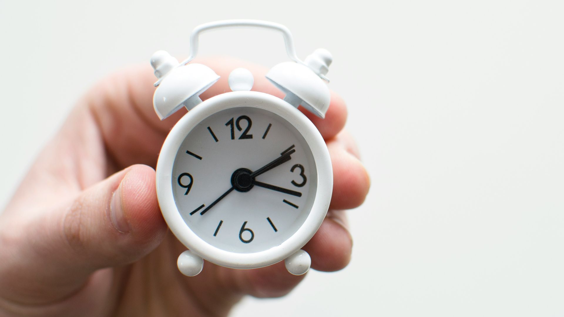 person holding white mini bell alarmclock