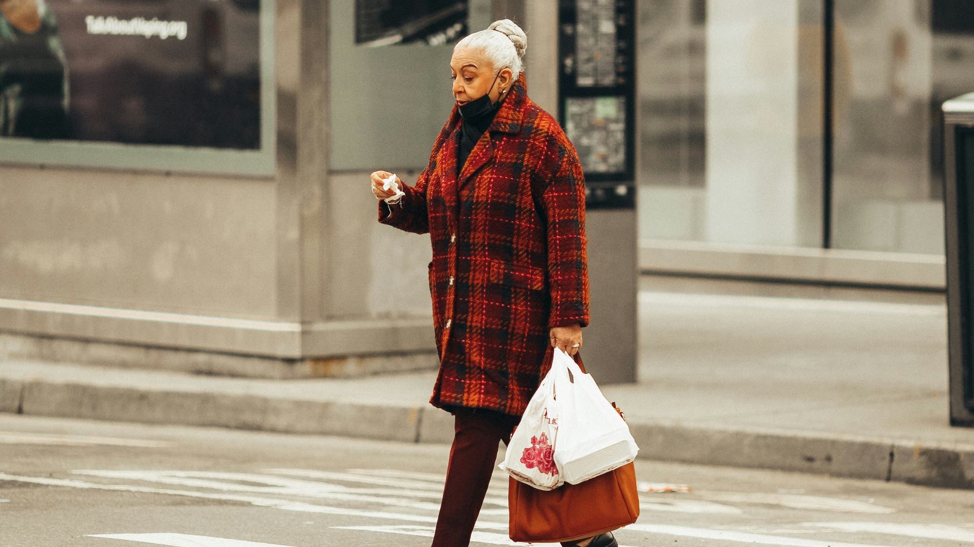 man in red and black plaid dress shirt and white pants walking on pedestrian lane during