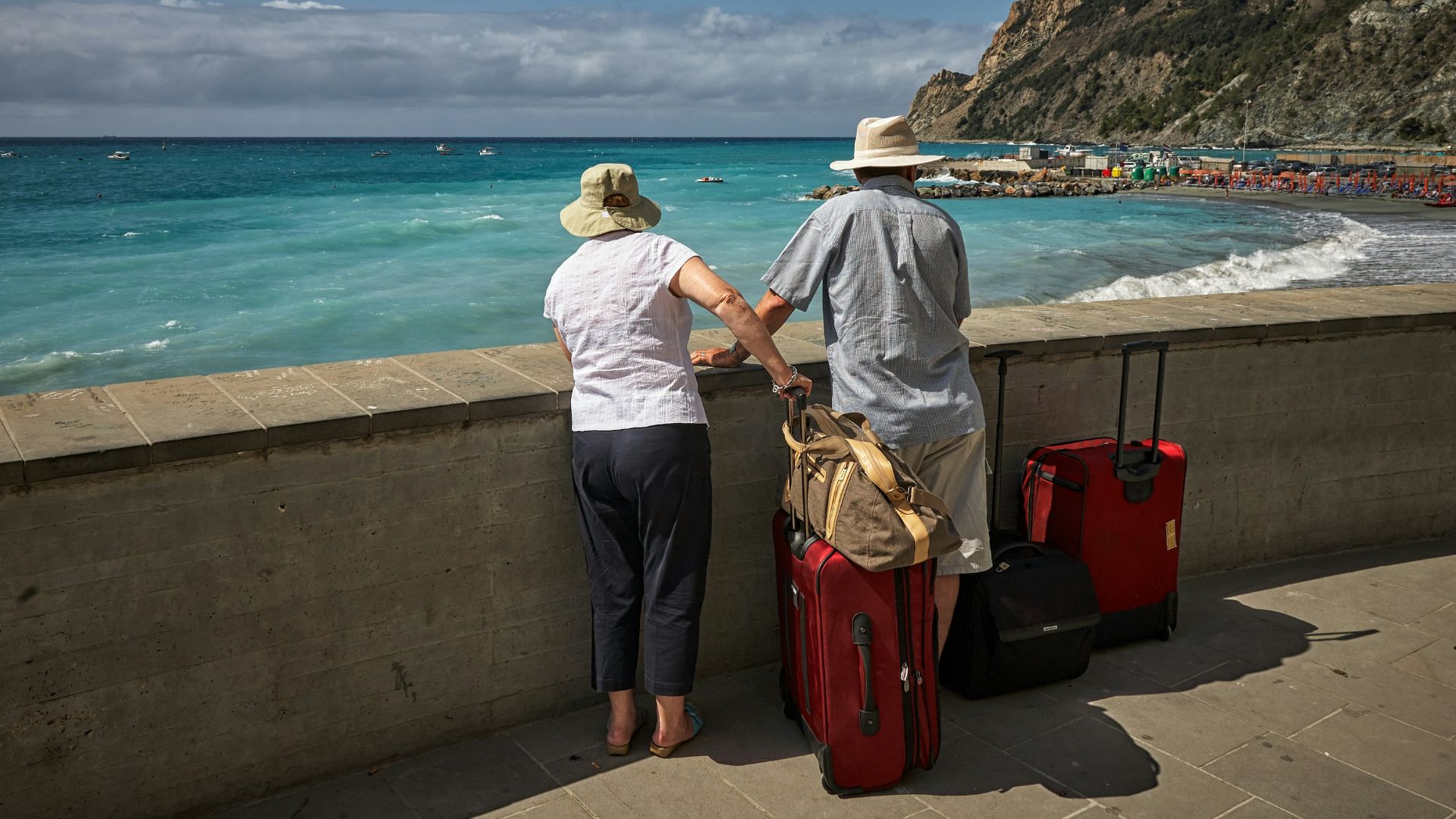 man and woman standing beside concrete seawall looking at beach