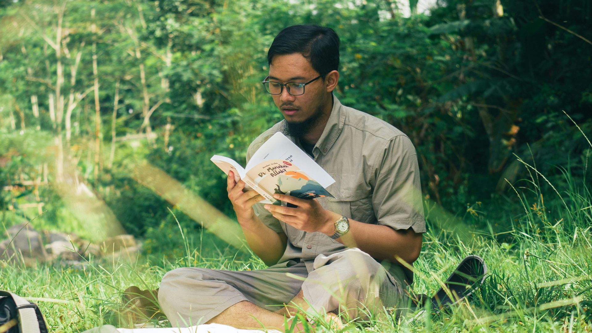 a man sitting in the grass reading a book