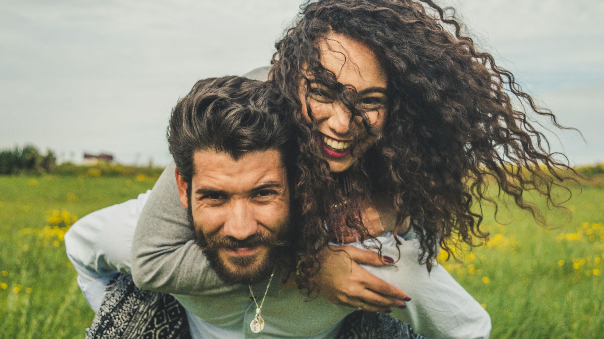 woman riding on man's back on green field