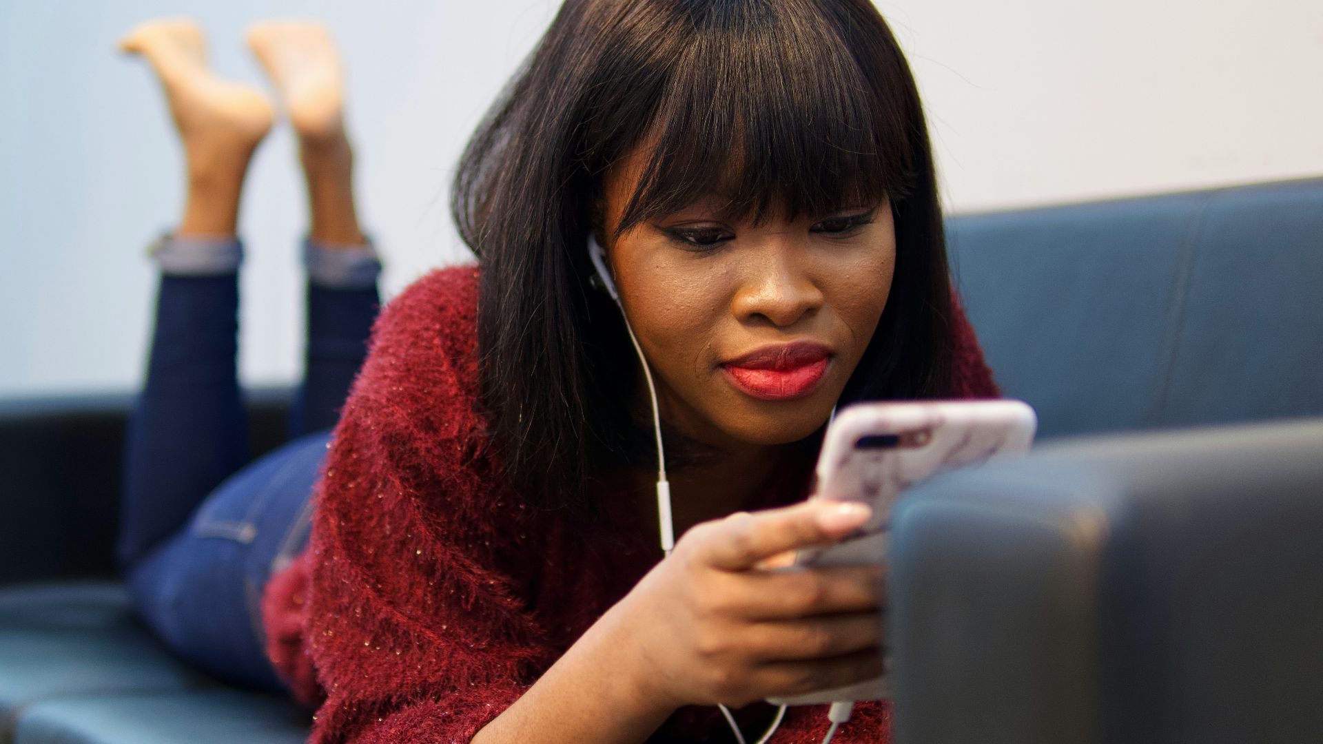 woman in blue sweater using white earbuds