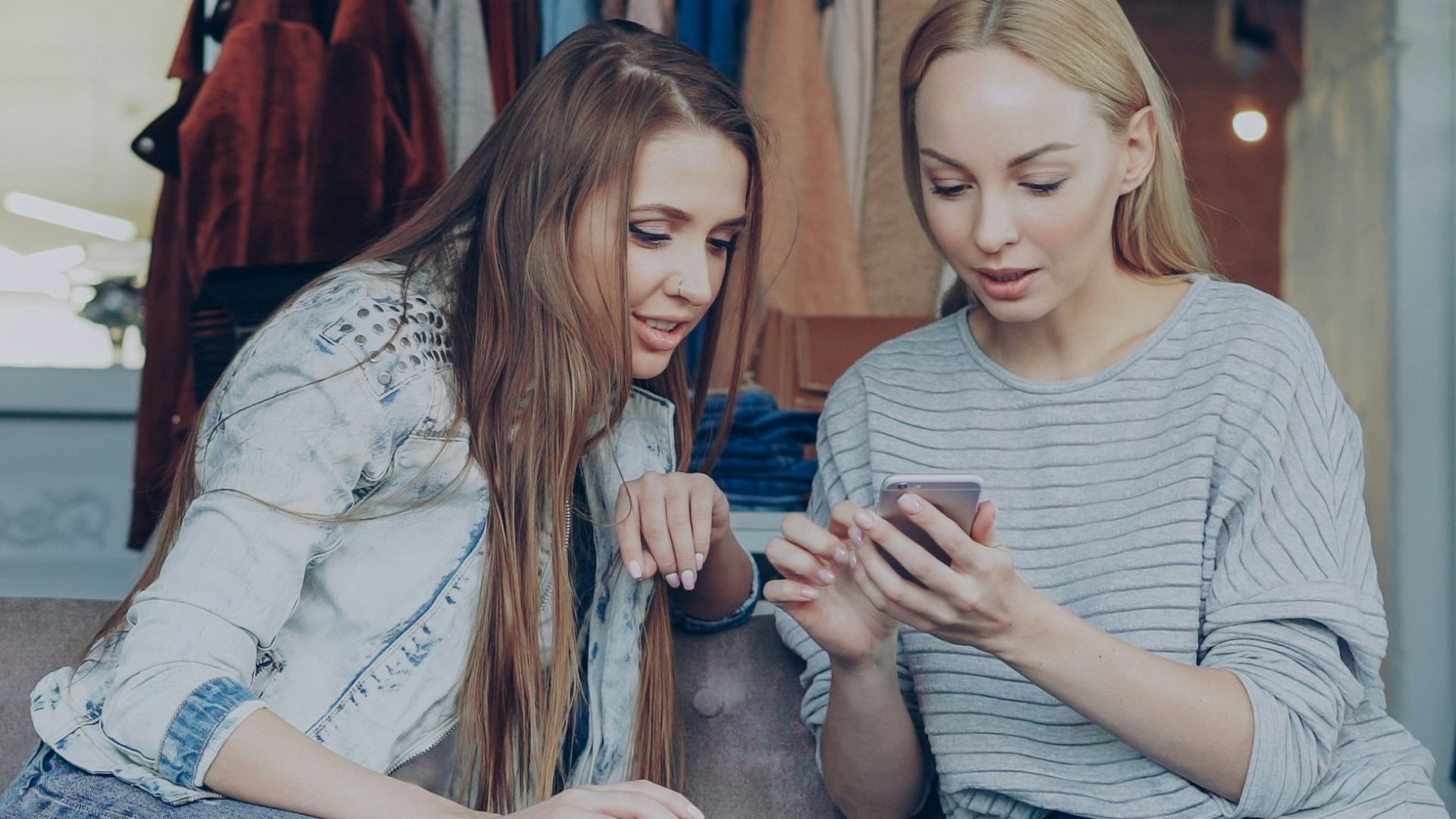 Two women are looking at a phone in a store.