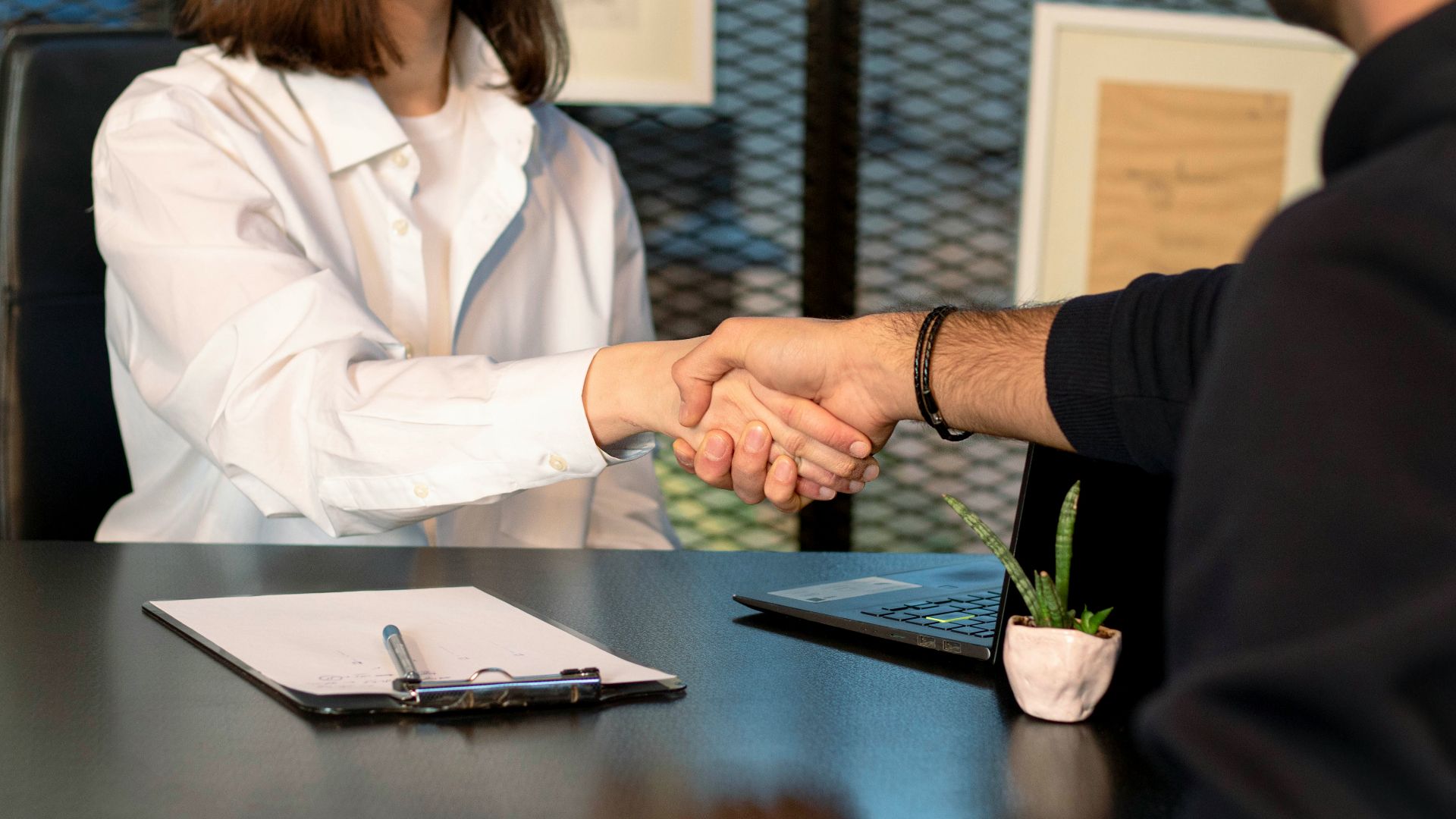 a man and a woman shaking hands in front of a laptop