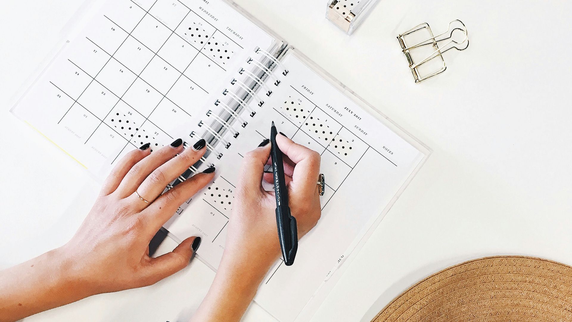 person holding ballpoint pen writing on white paper