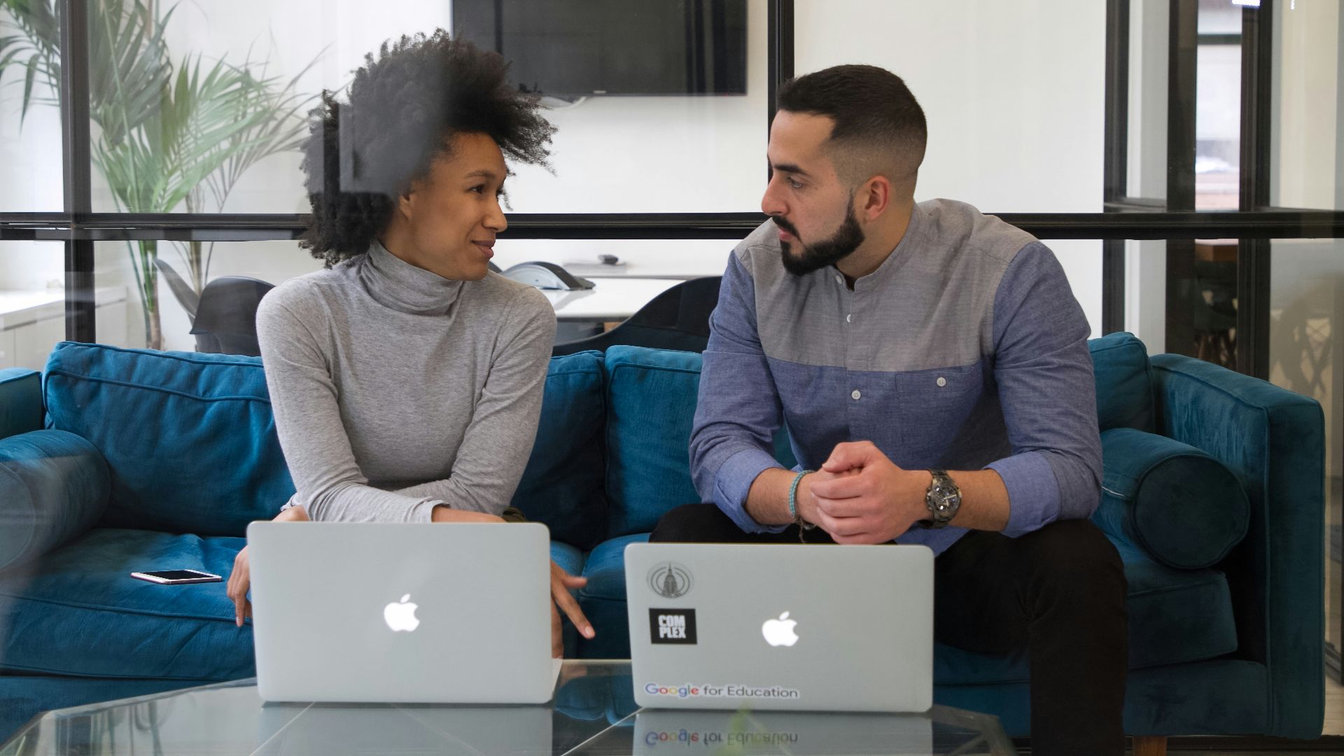 a man and a woman sitting on a couch with laptops