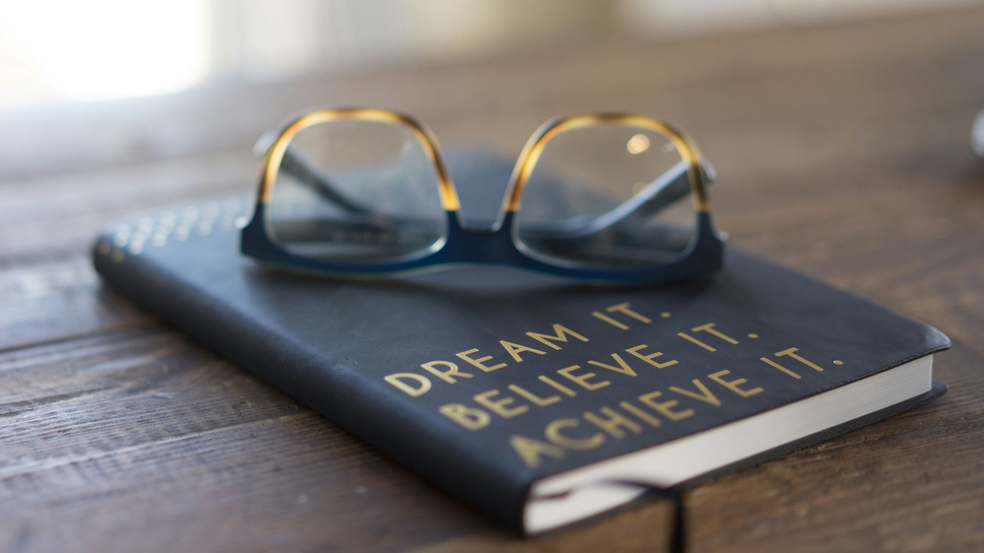 black and brown eyeglasses on book on brown wooden table