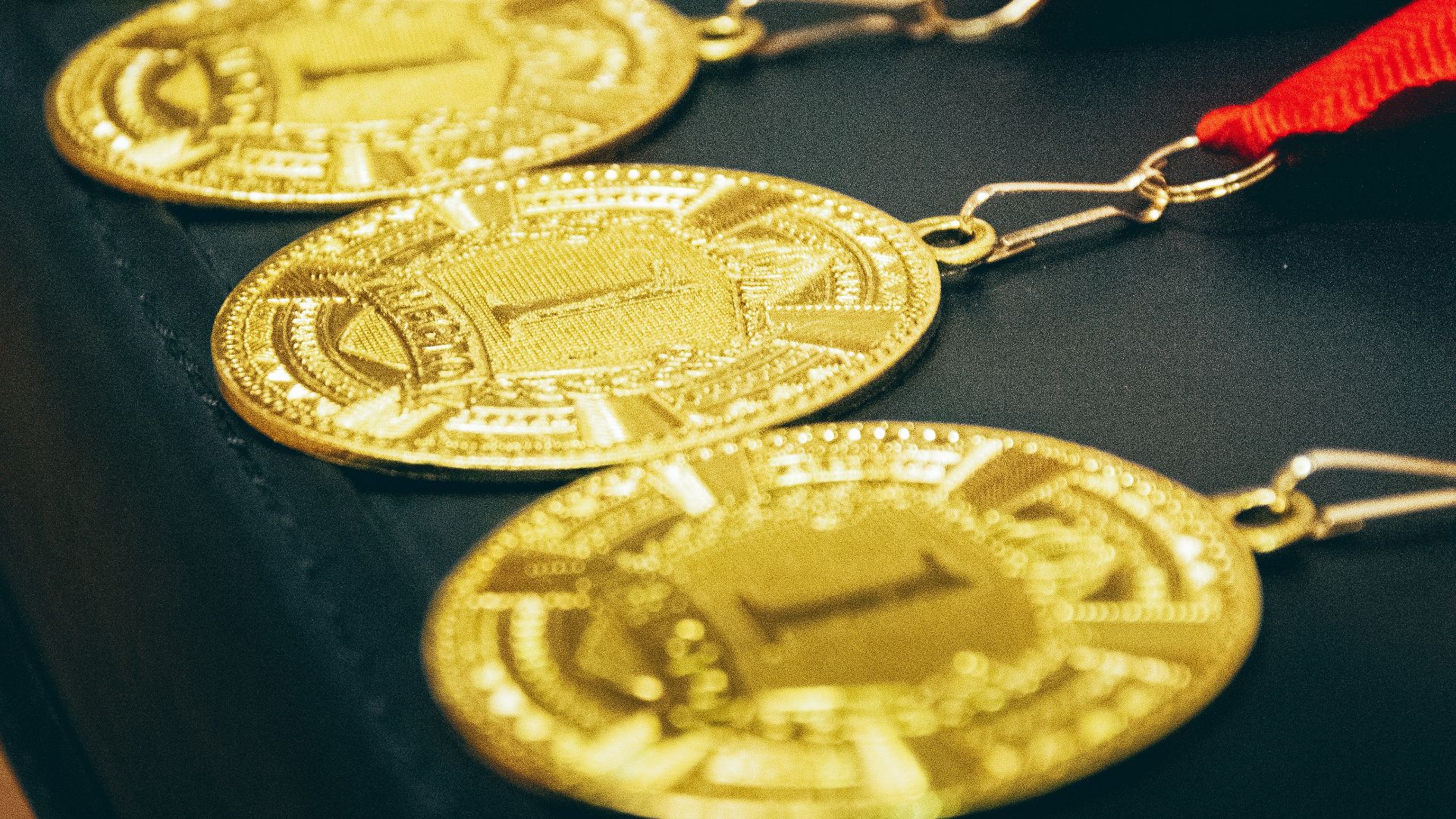 a row of gold medals with a red ribbon