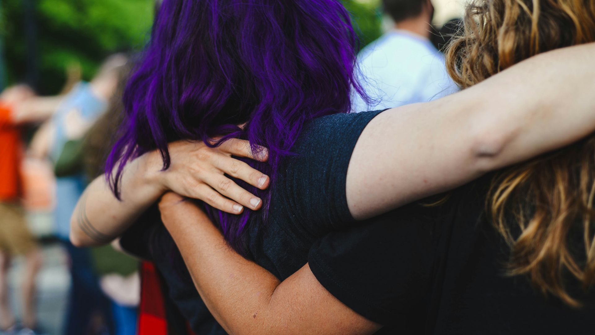 woman in black t-shirt covering face with purple hair
