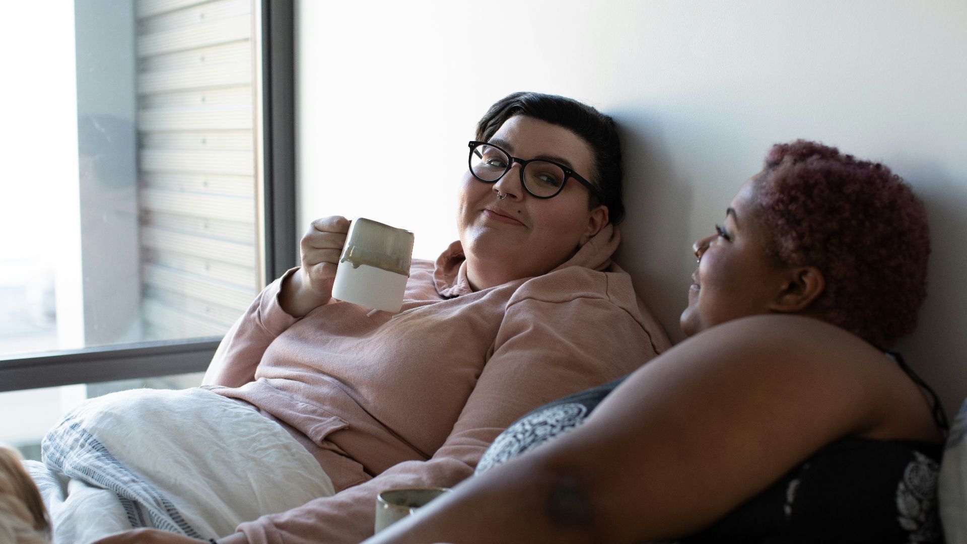two woman lying on bed