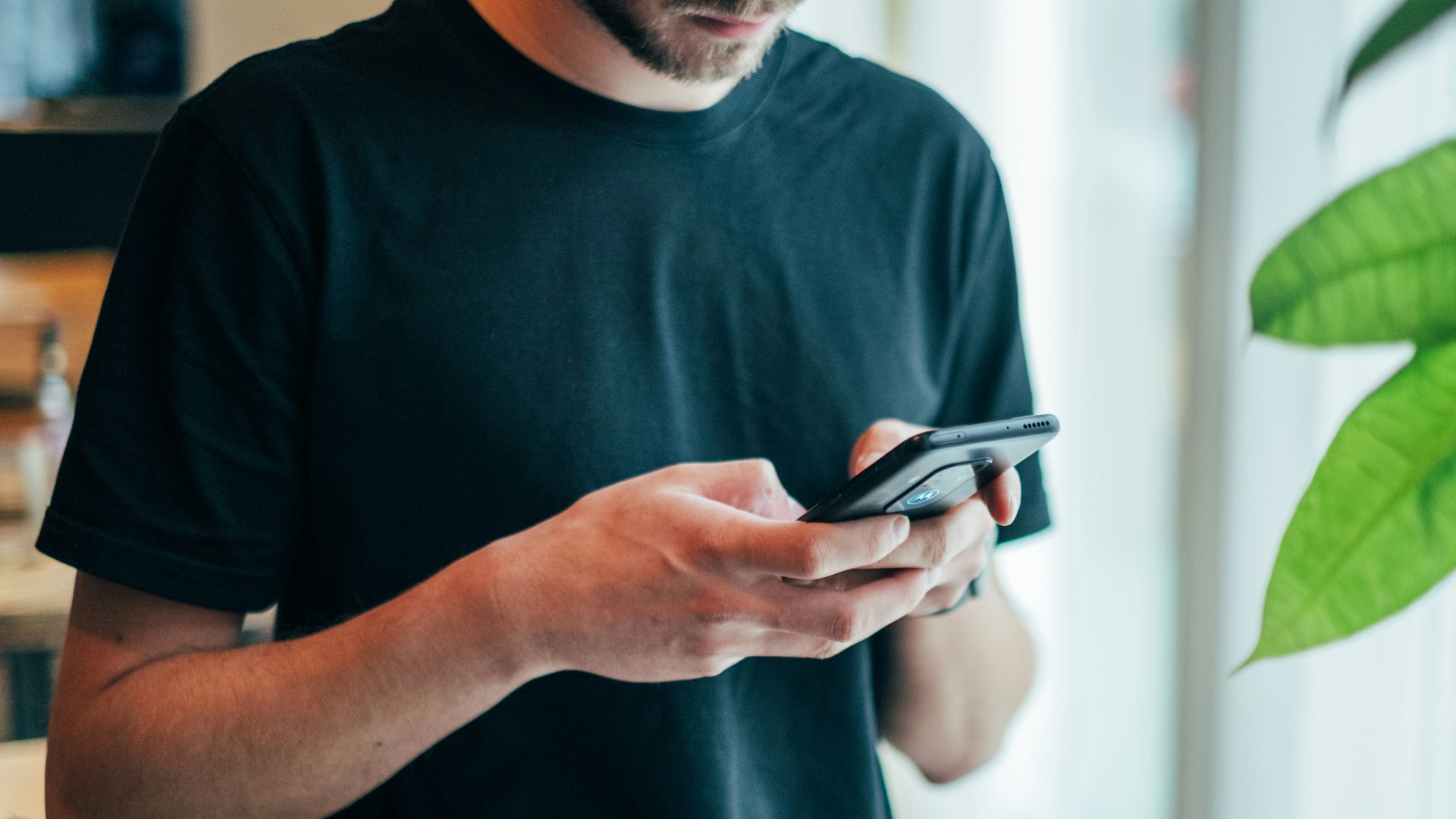 man in black crew-neck top using smartphone