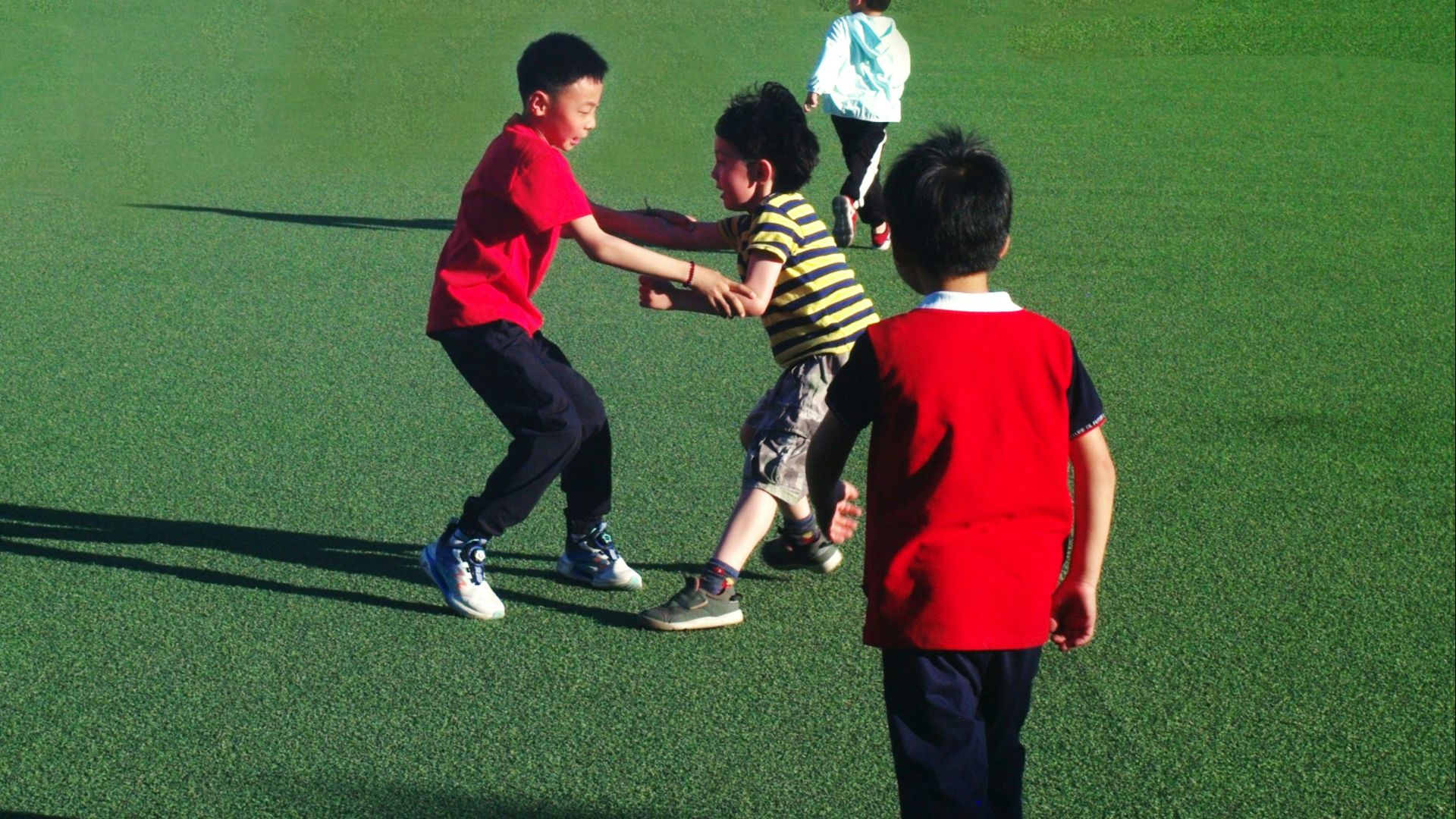 Children are playing together on a green field.